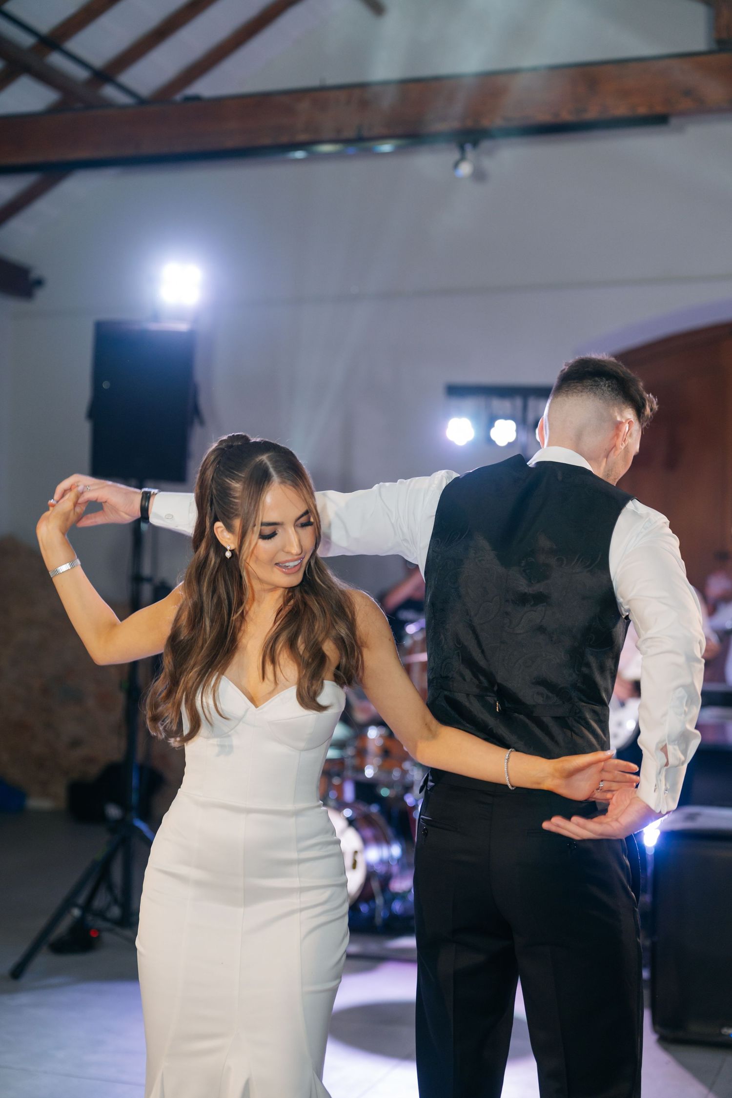 Elegant couple performs their first dance at an indoor wedding reception.