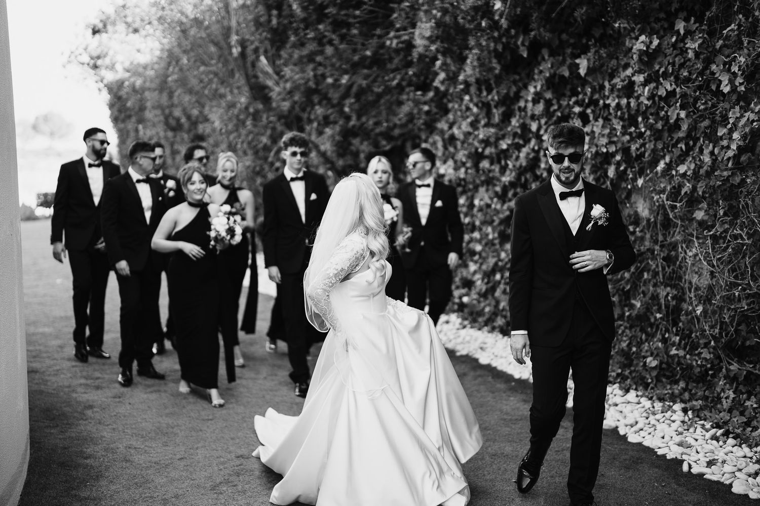 Wedding party walks together outdoors in formal black and white attire.