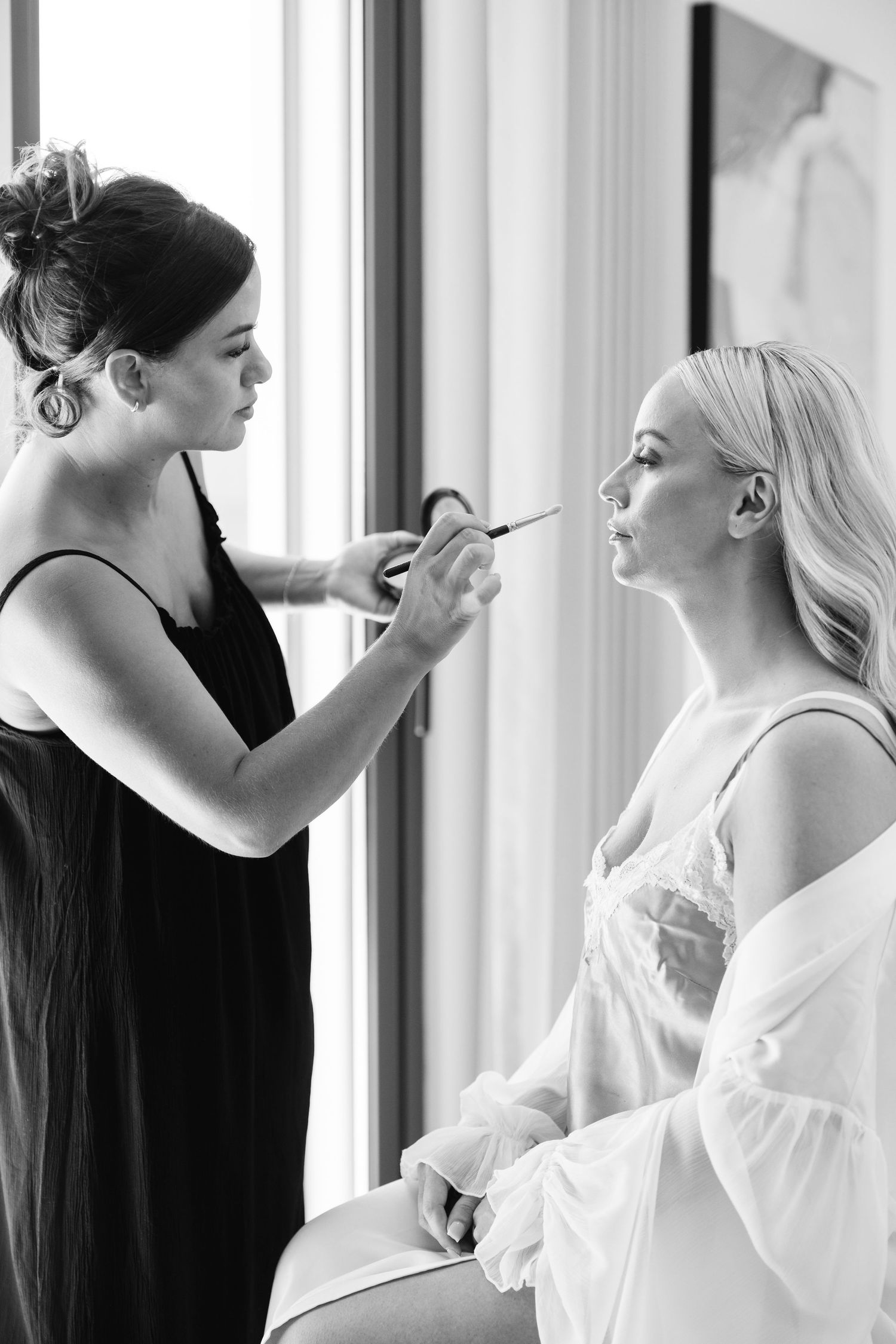 Behind the scenes shots of bridal makeup application near sunlit windows.