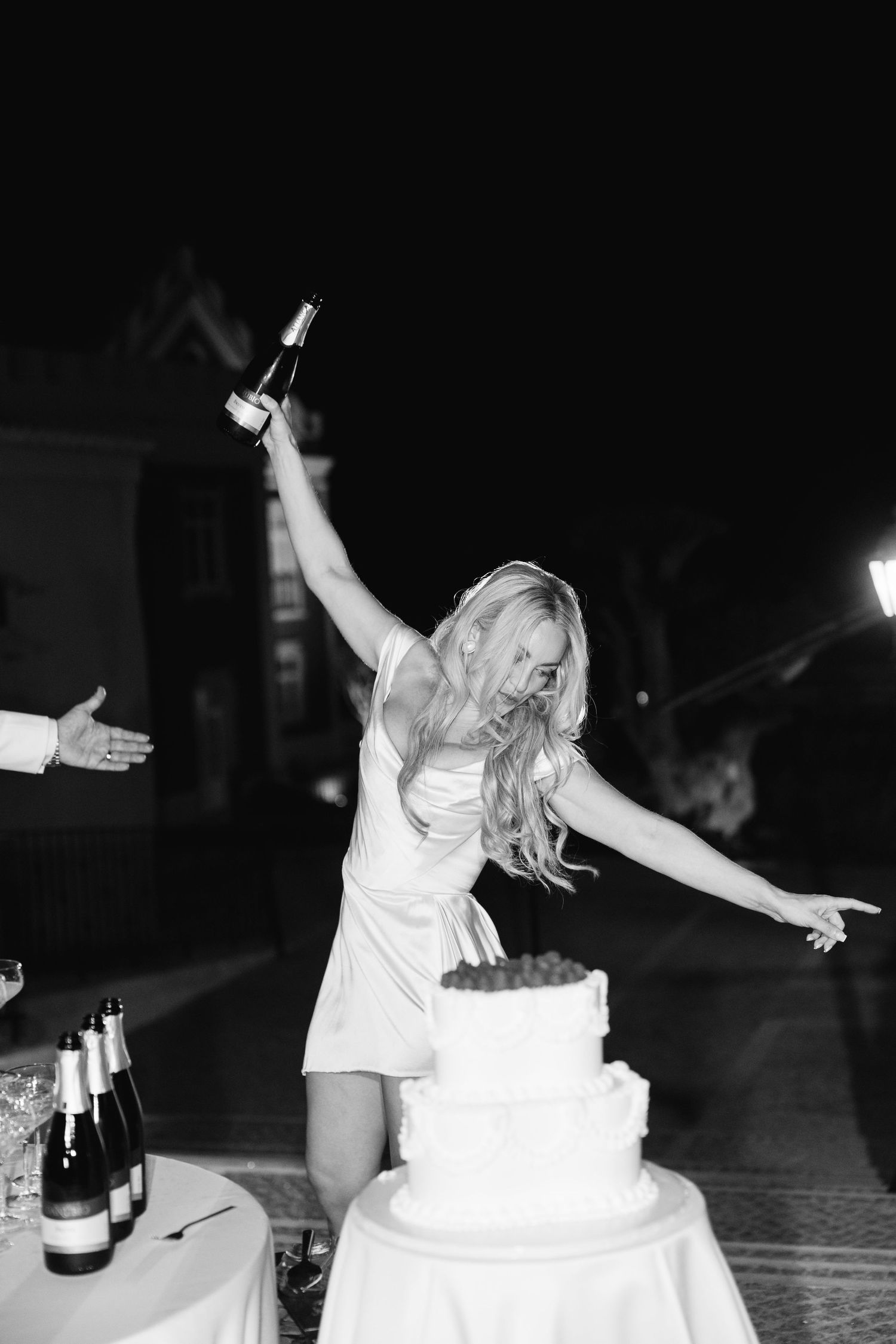 A celebratory moment near a wedding cake with champagne bottles on display.