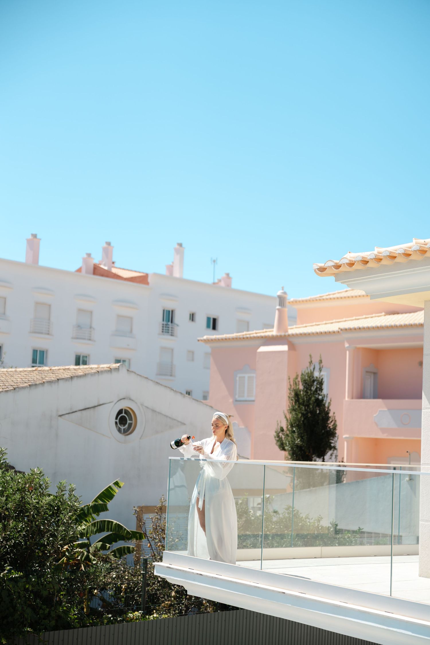 Ethereal bridal portraits on balcony against Mediterranean white architecture.