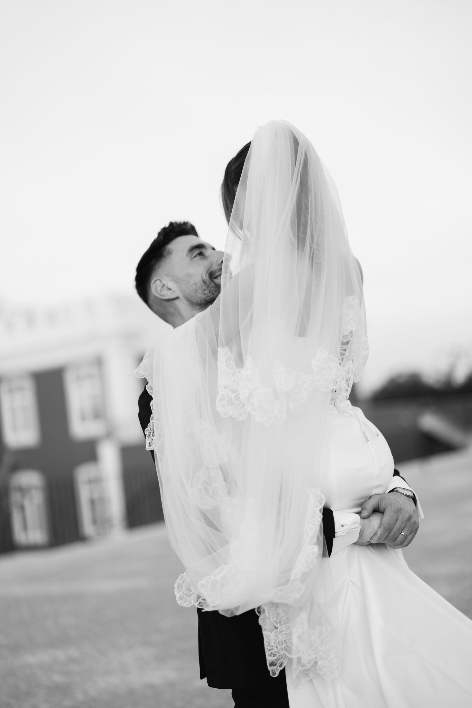 A romantic black and white wedding photo series showing tender moments between a bride and groom under a flowing veil.
