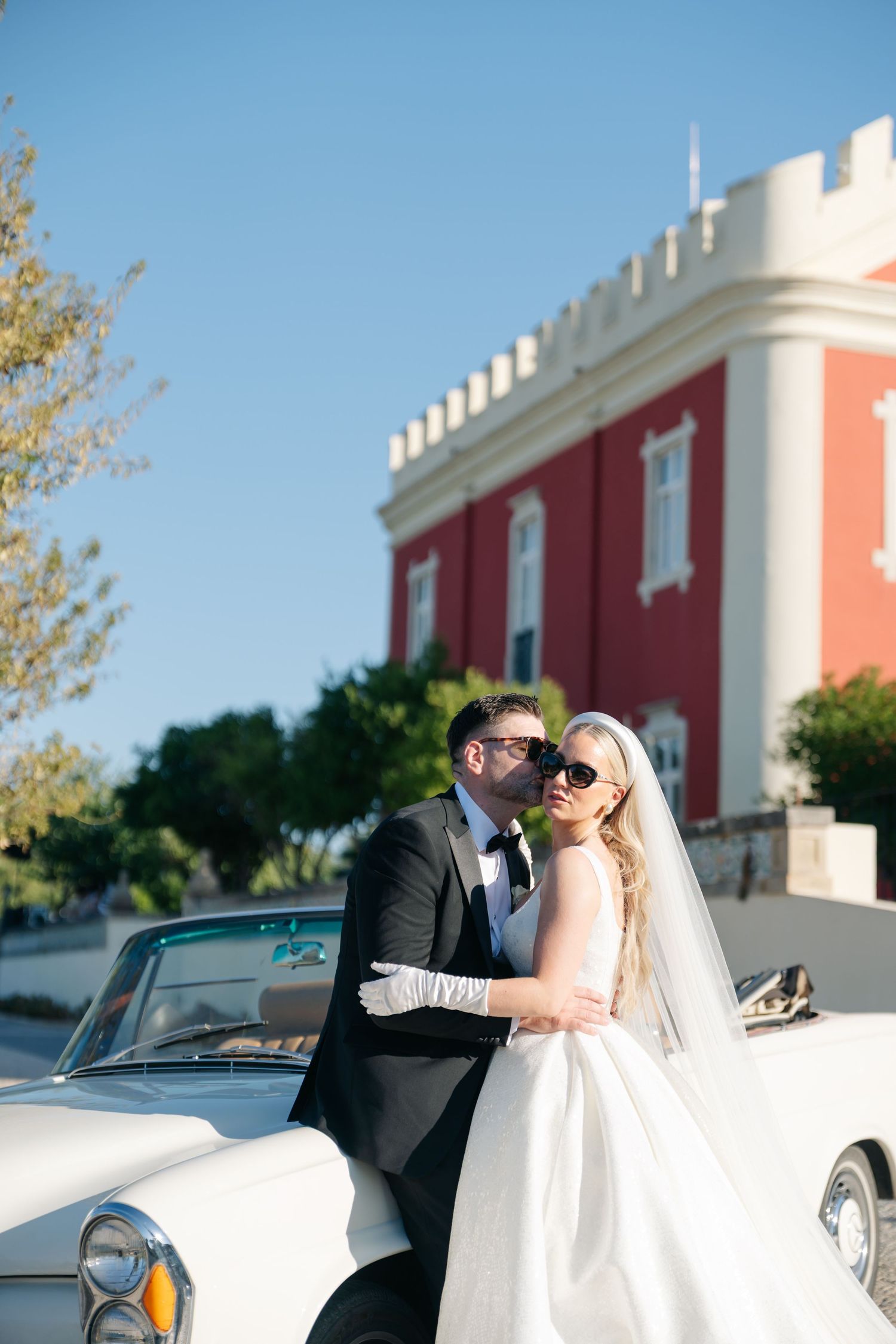 Romantic wedding photos with classic car and coral building in background.