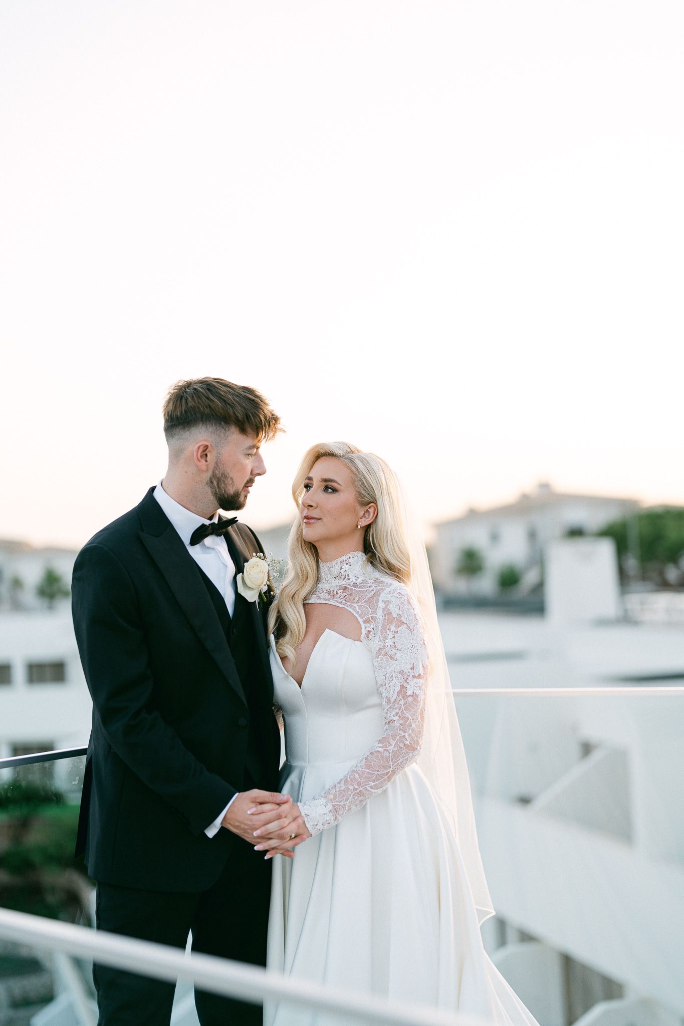 Romantic wedding couple shares intimate moment on rooftop at dusk.