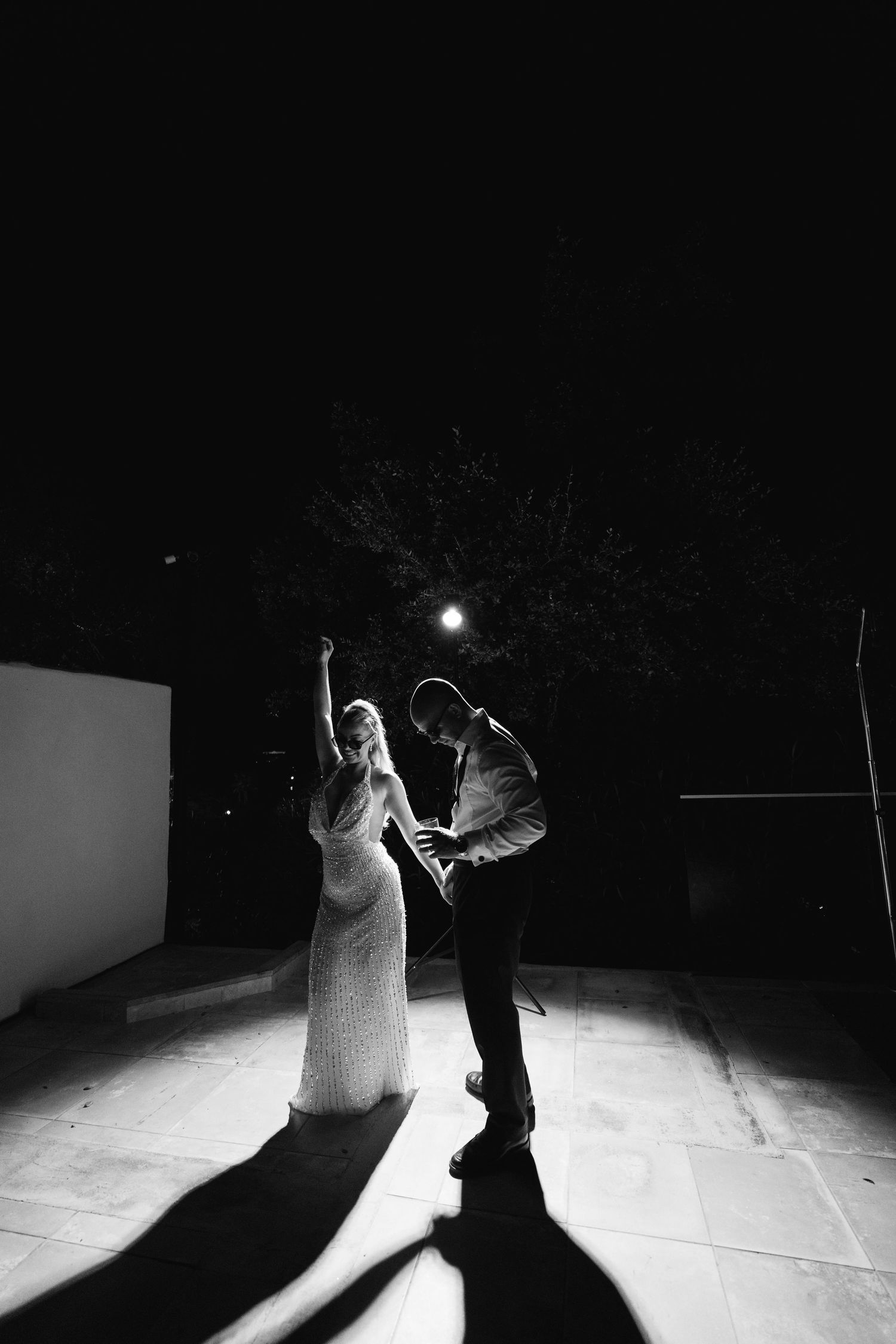 Dramatic black and white silhouettes of a couple dancing at night under spotlights.