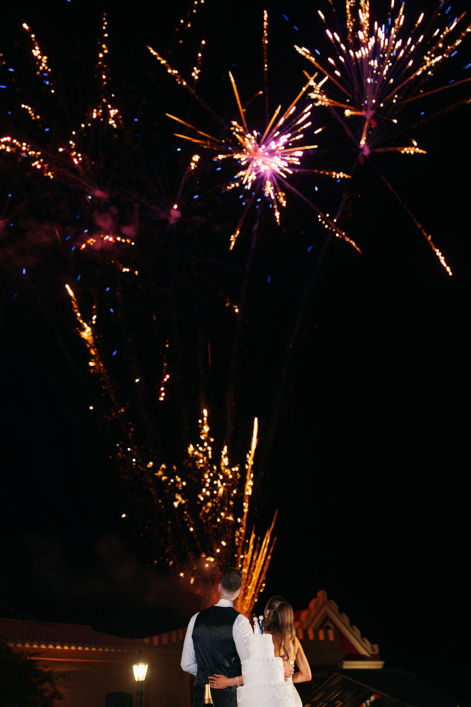 Colorful fireworks display illuminates the night sky during a wedding celebration.