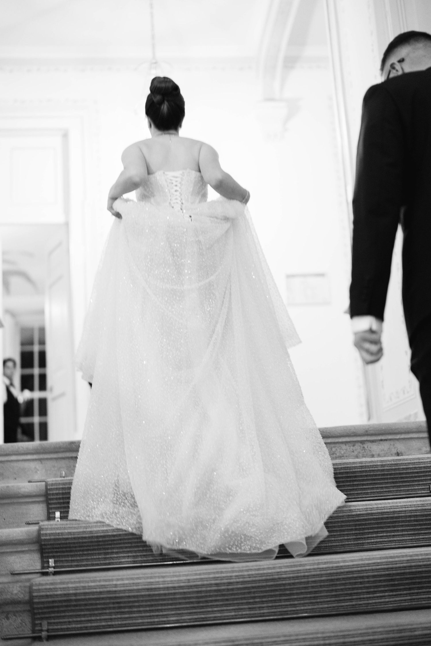 A black and white collage of a bride's dress flowing down stairs during a wedding ceremony.