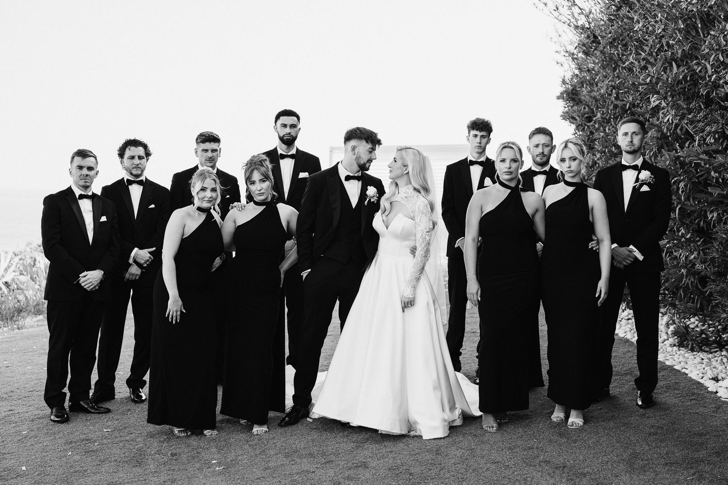 Wedding party arranged in casual poses for outdoor group photography session.