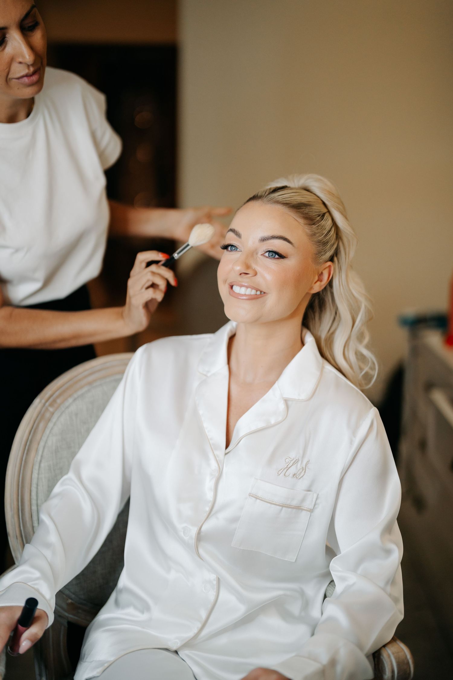 Candid moments captured during bridal makeup application in white robe.