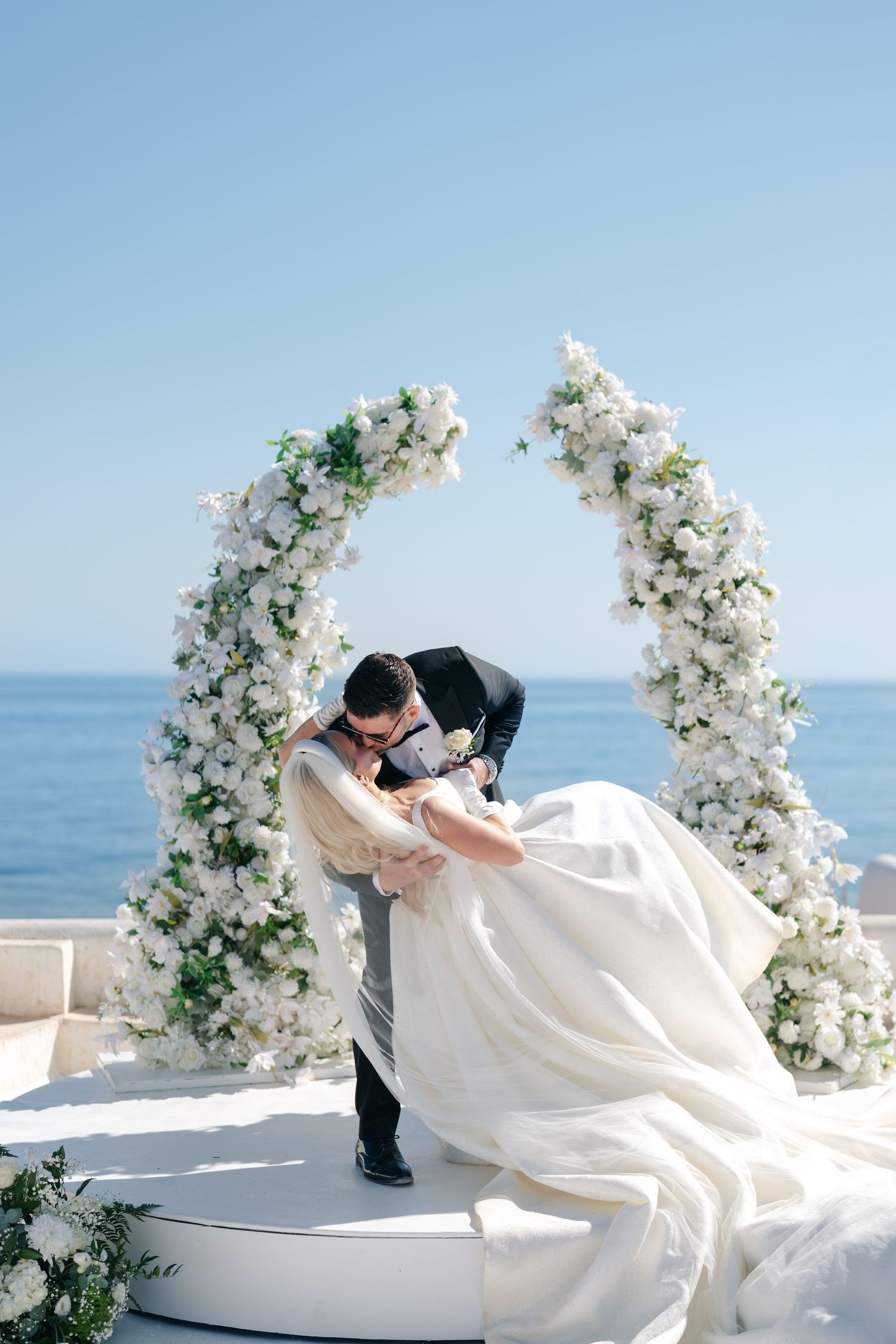Dramatic wedding portraits on a white terrace overlooking the Mediterranean Sea.