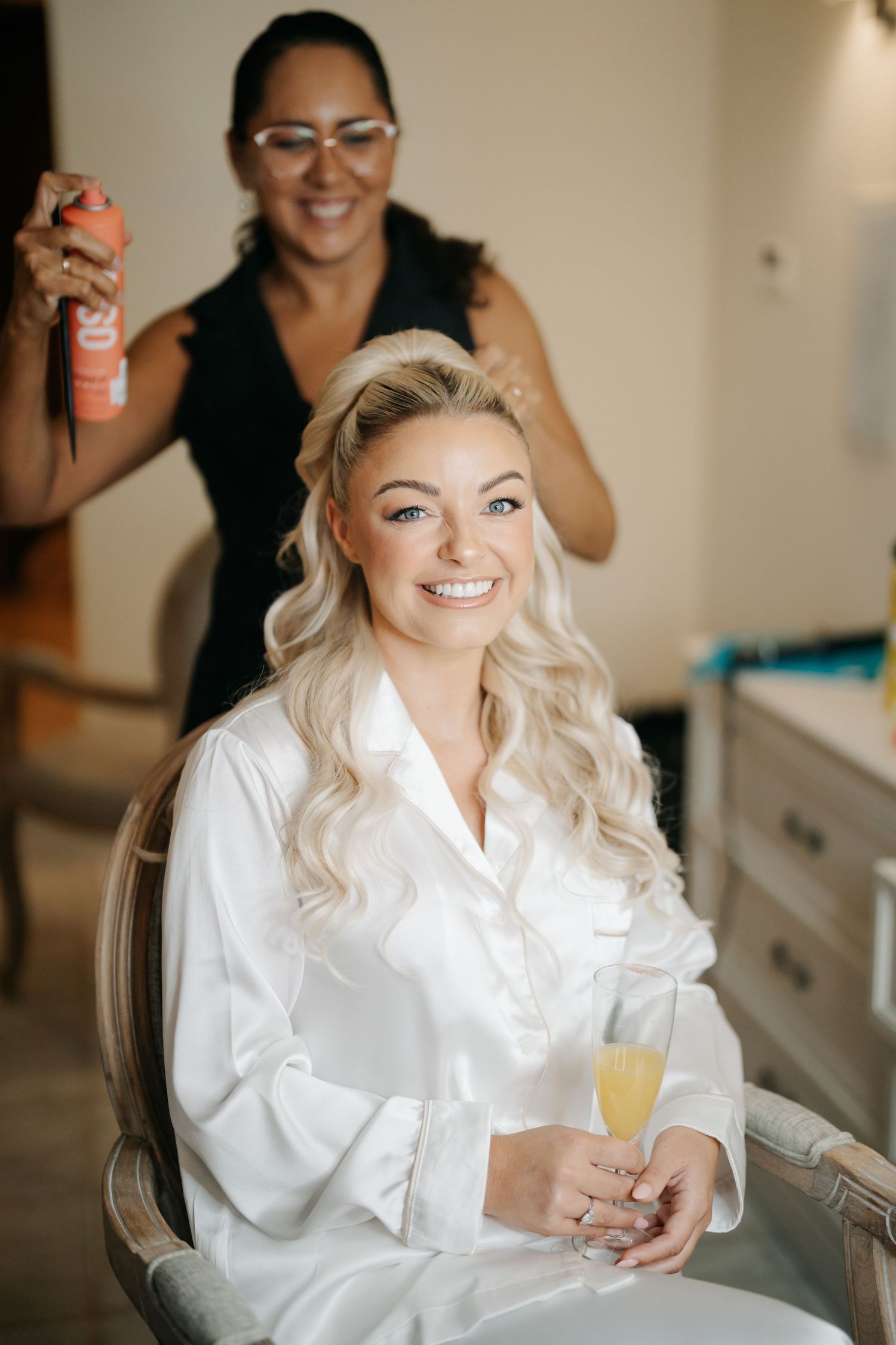 Getting ready scene with champagne and laughter during wedding preparations.