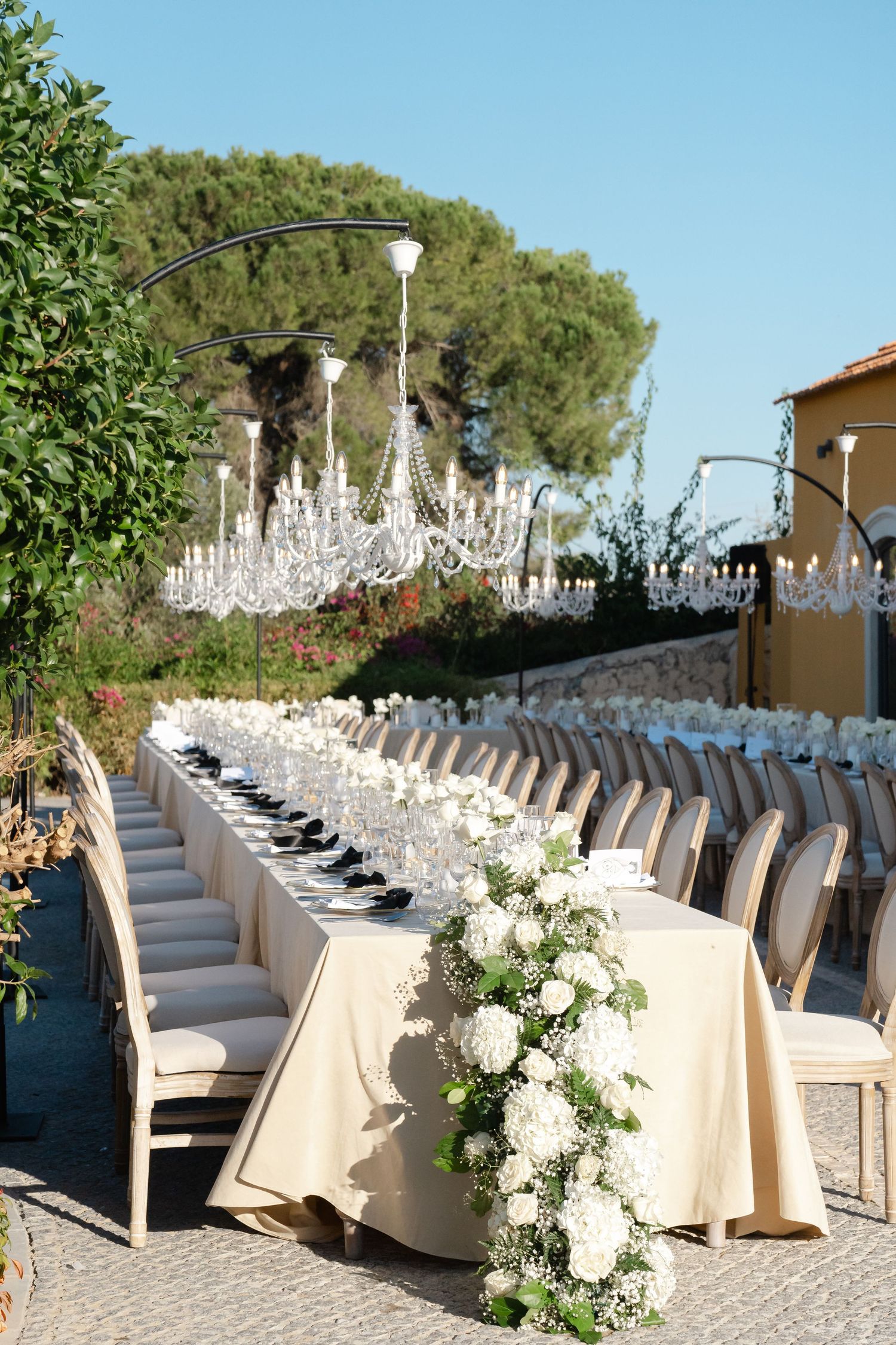 Long wedding reception table with white floral arrangements and elegant place settings.