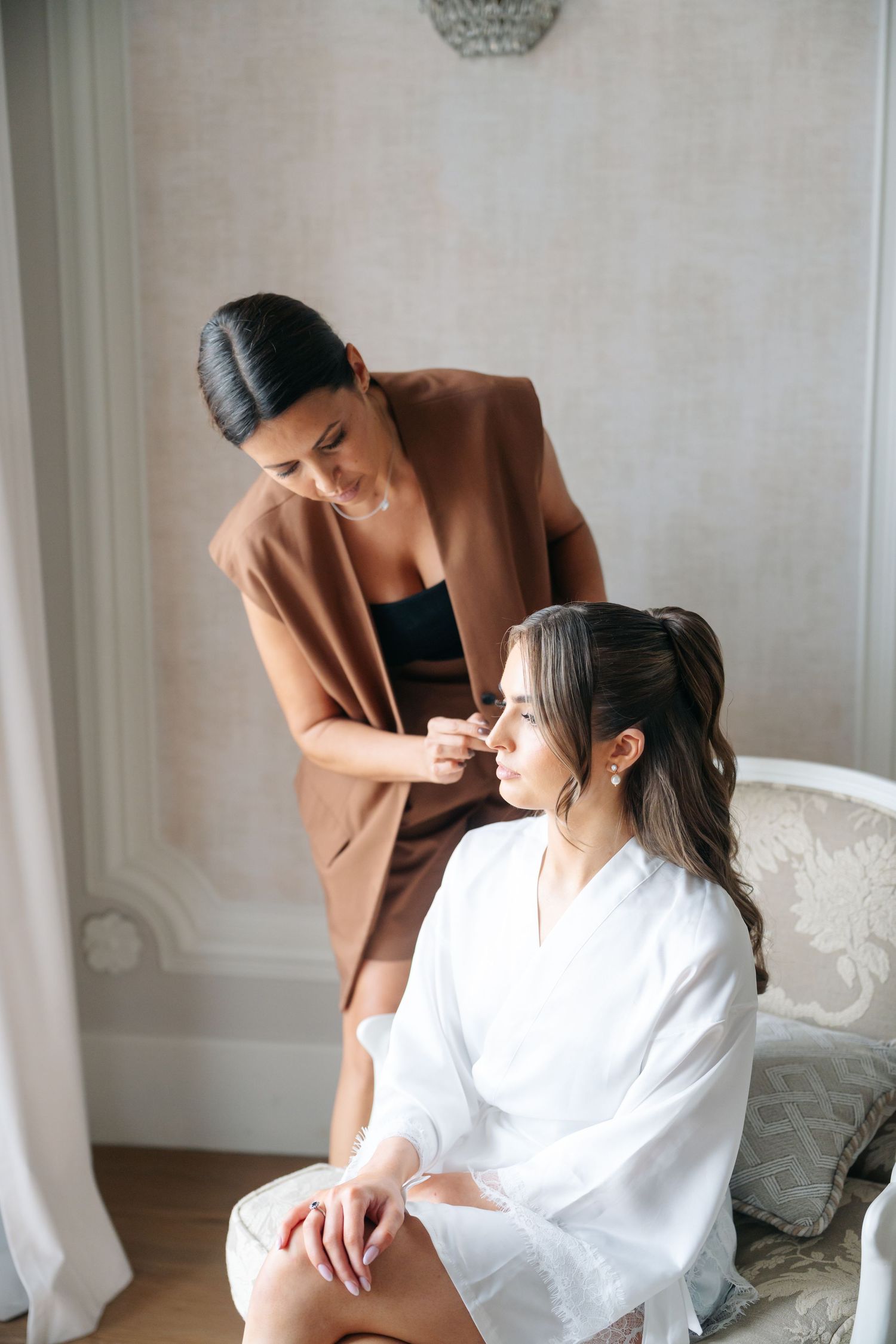Professional styling session in elegant white room with crystal chandelier.