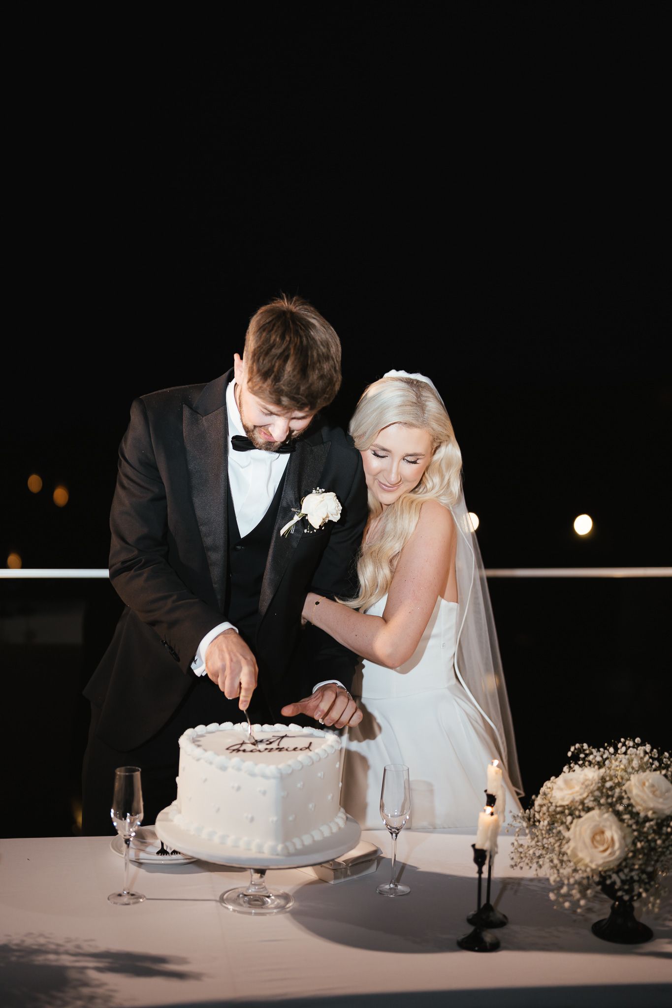 Newlyweds cutting their white wedding cake together at the reception.