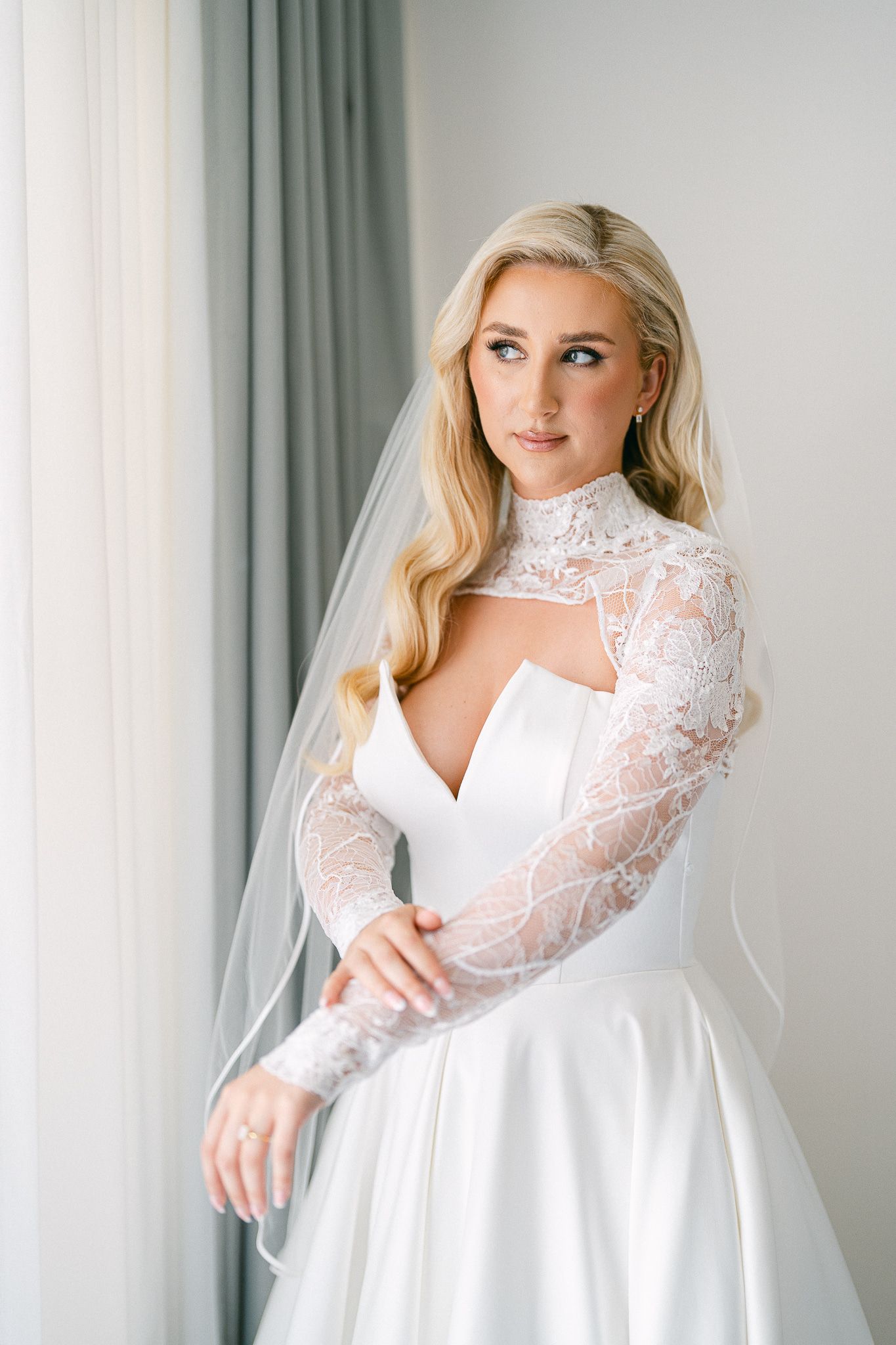 Romantic bridal portrait showcasing a structured wedding gown with intricate lace sleeve details.