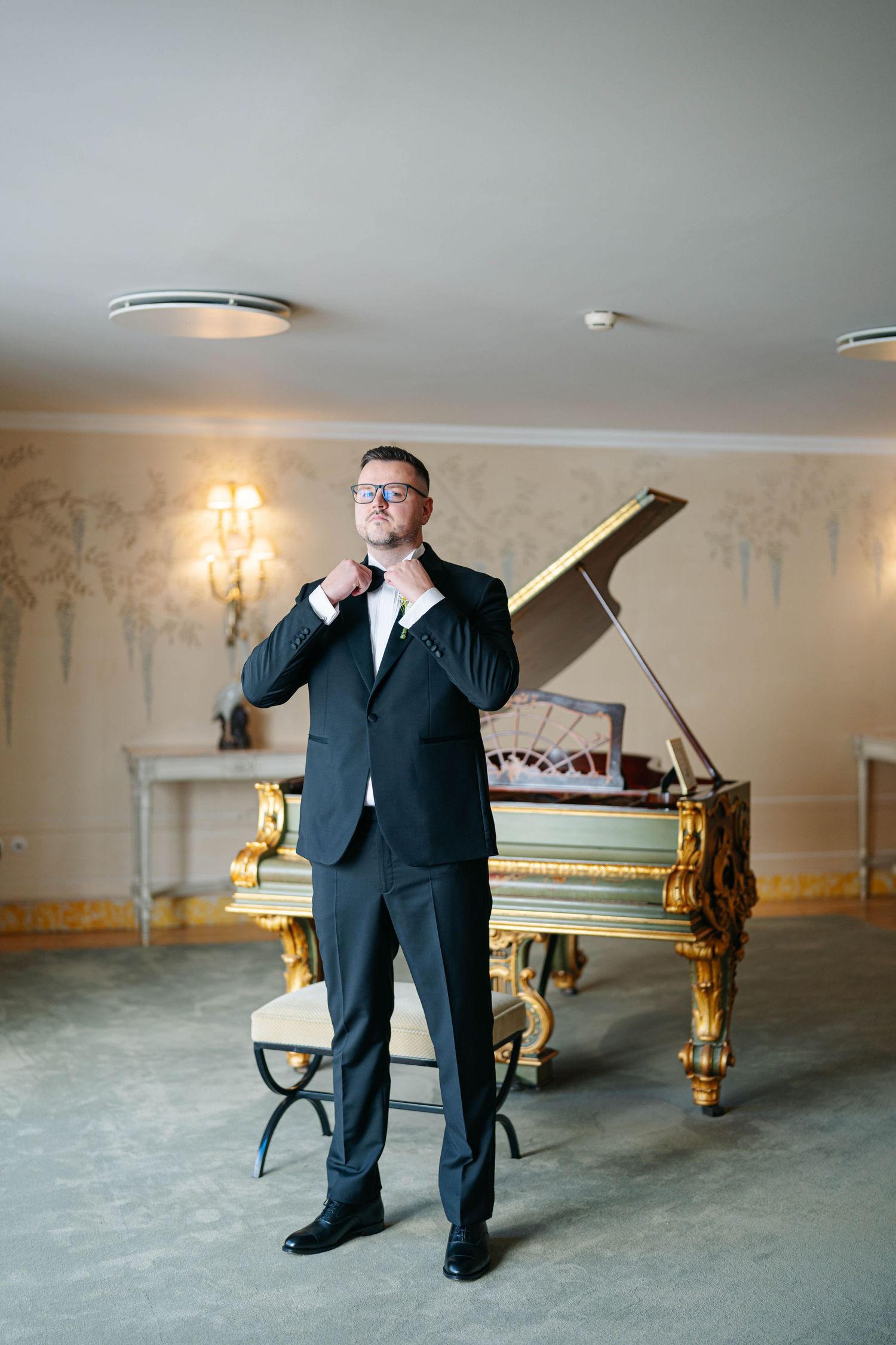 Formal ballroom interior with a grand piano and ornate gold detailing.