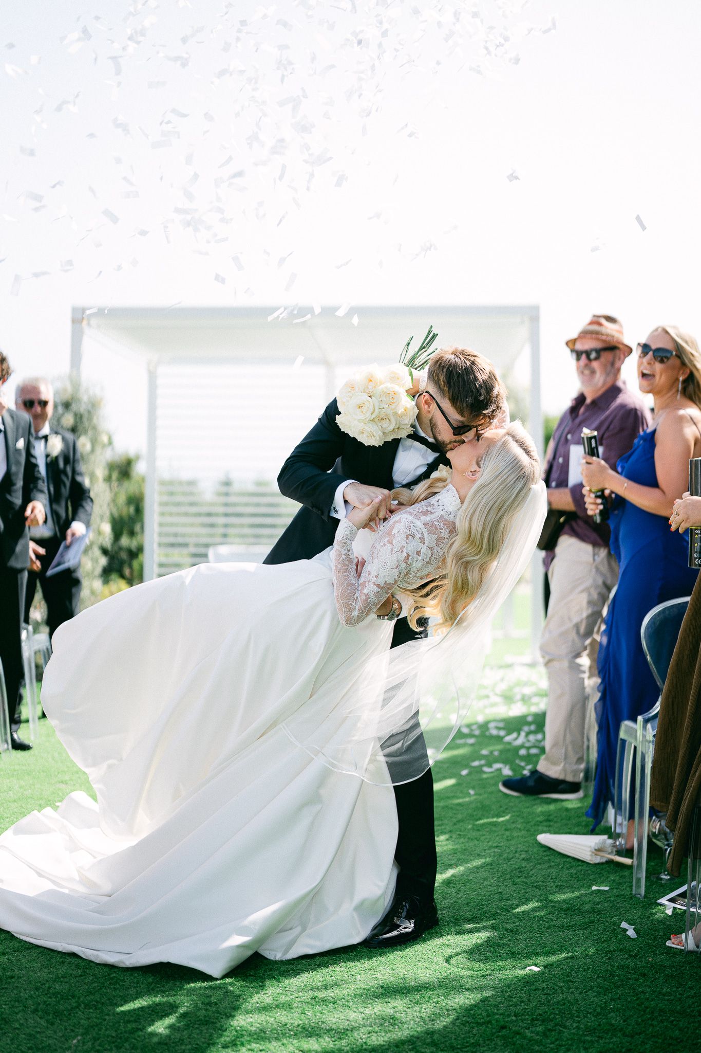 Wedding party reacts with joy during the couple's first dance on artificial turf.