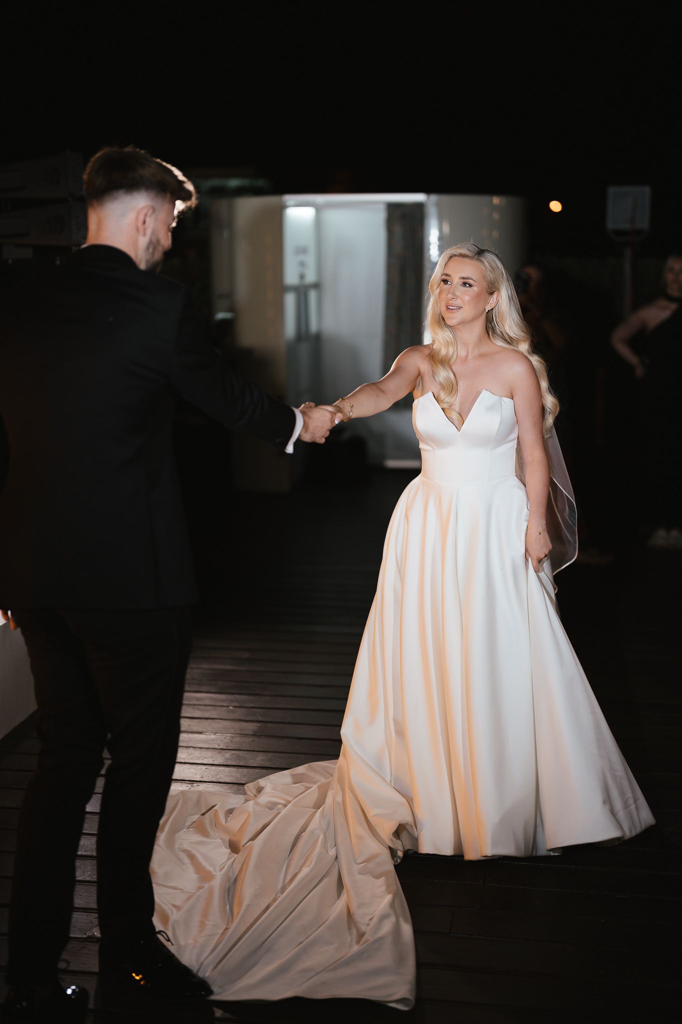 Wedding reception scene with a flowing white bridal gown in dramatic lighting.