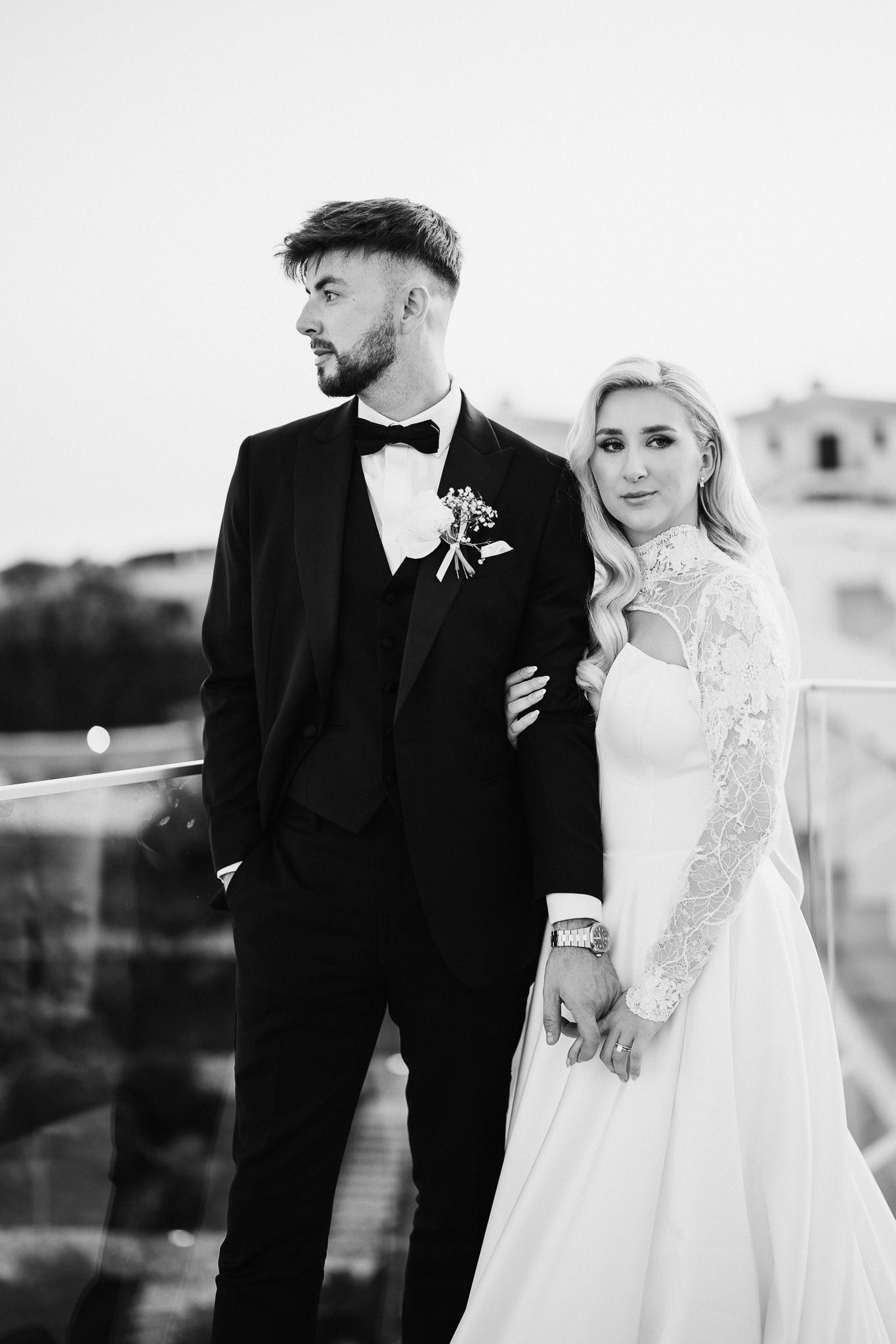 Black and white wedding portraits capture tender moments between newlyweds on an outdoor terrace.