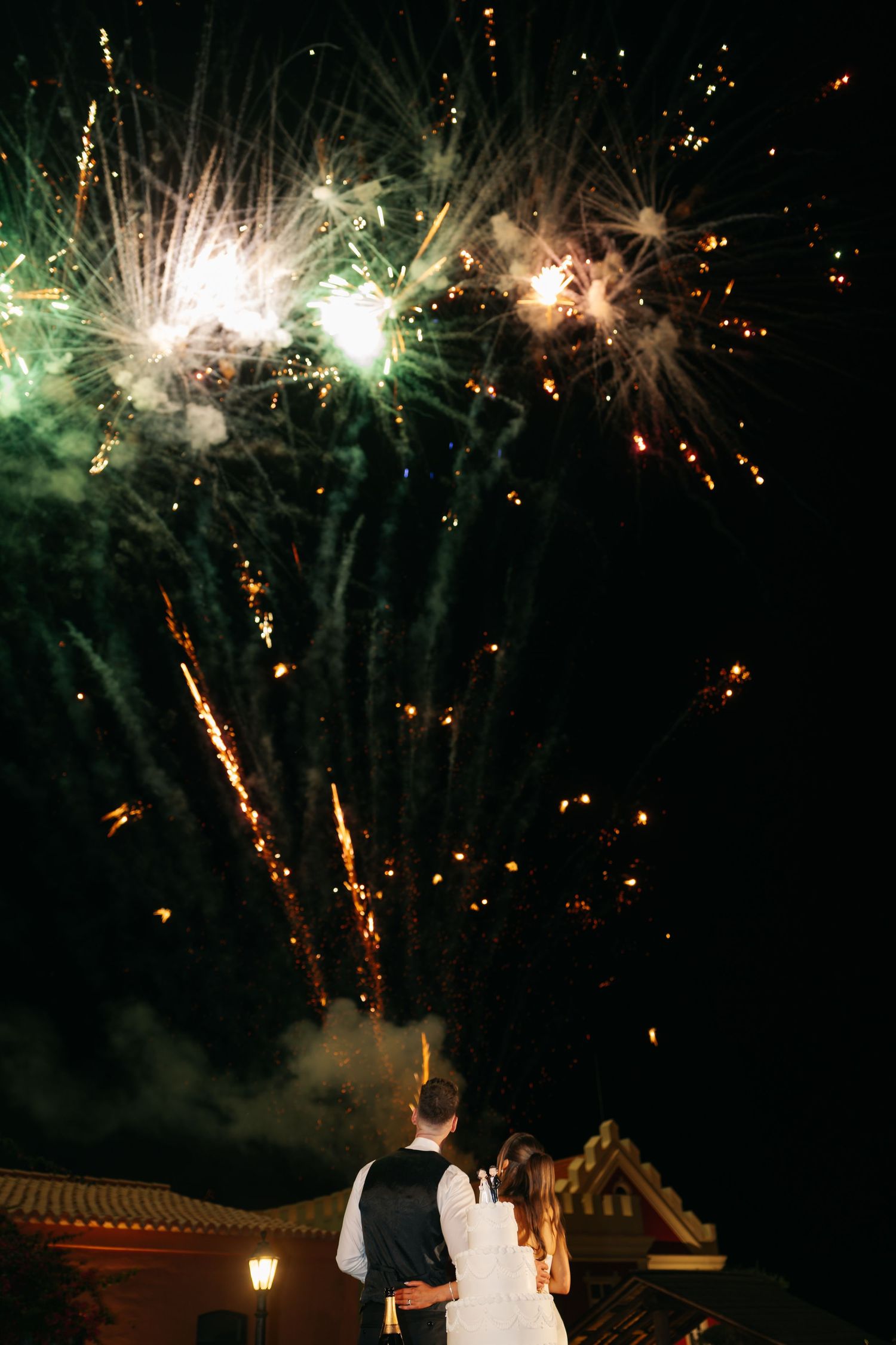 Spectacular white and gold fireworks light up the night sky at an outdoor wedding.