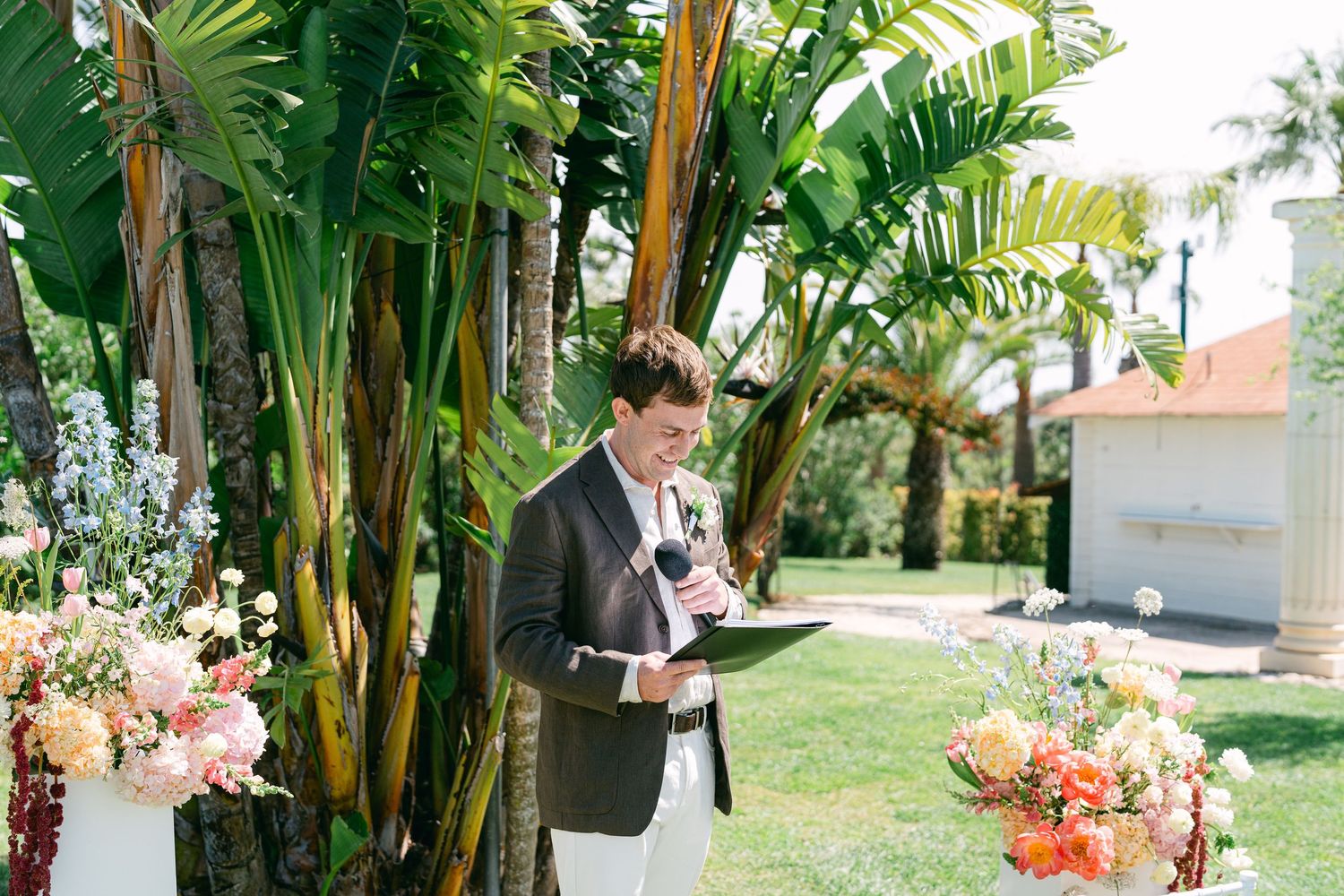 Tropical palm trees and floral decorations line an outdoor wedding venue.