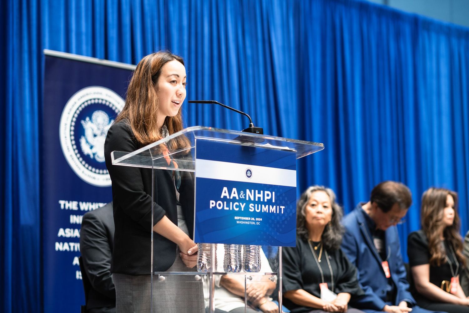 Woman speaks at podium during AA and NHPI Policy Summit at the White House initiative conference.