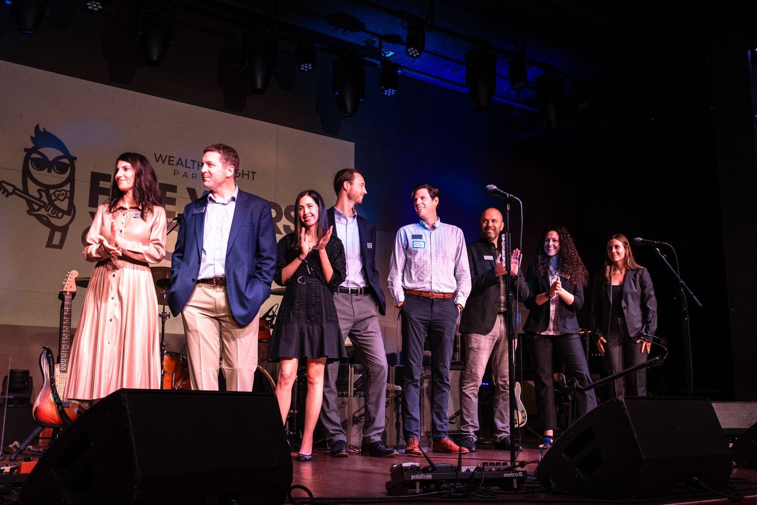 Group of professionals on stage at Wealth Insight Partners Five Years & Rock-N Roll anniversary celebration event.