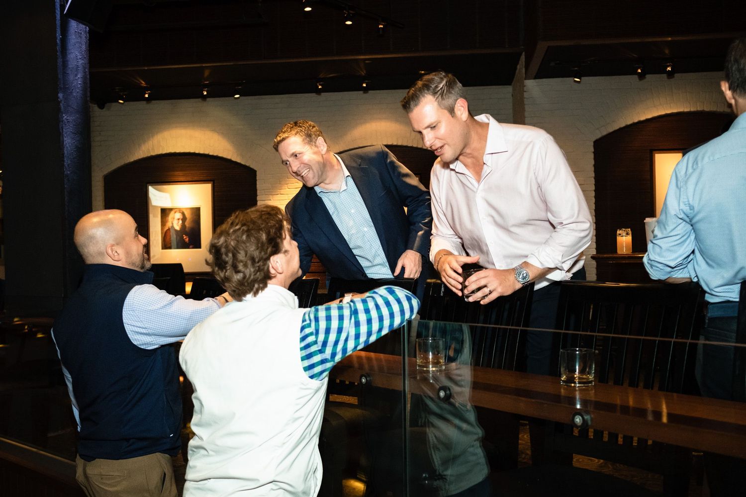 Group of men engage in lively conversation at an upscale indoor venue event.