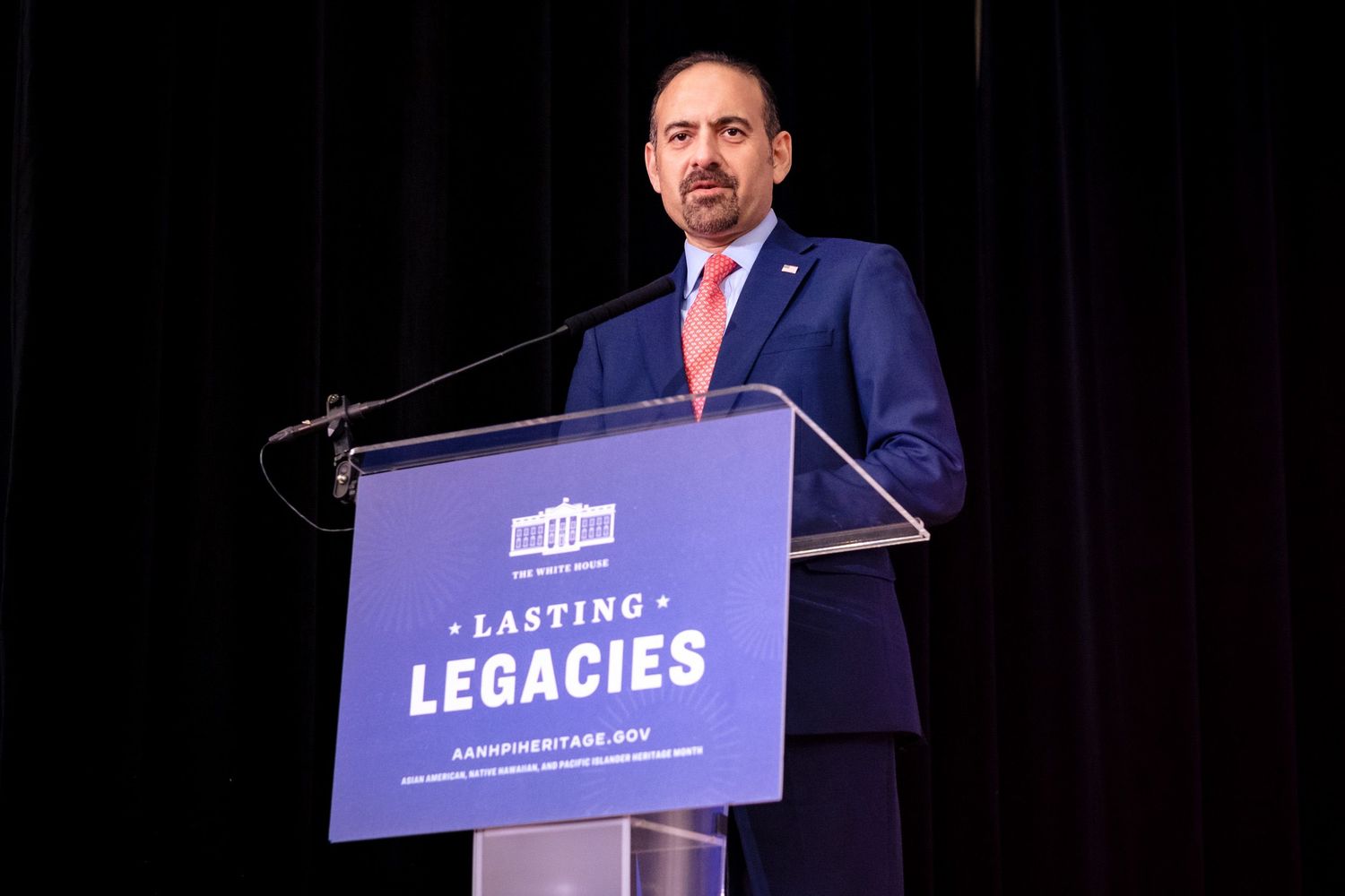 Man in suit speaking at podium during Lasting Legacies event at white house heritage conference.