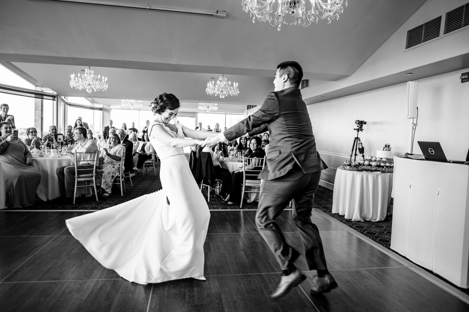 Bride and groom performing energetic first dance at elegant wedding reception.