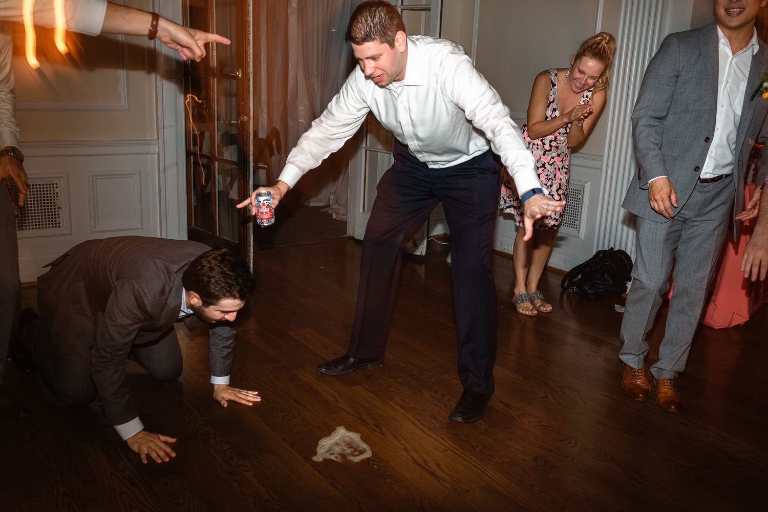 Lively wedding reception dance floor with guests doing the limbo under someone's arm.