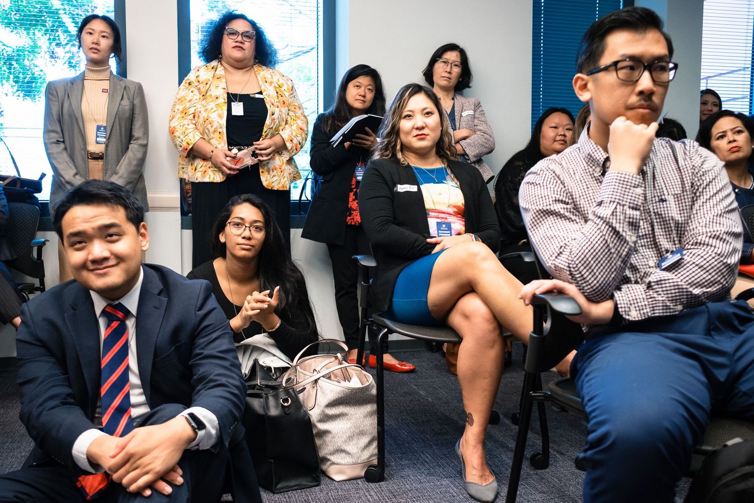 Diverse group of professionals attending a business seminar or conference, seated and listening attentively in a modern office.