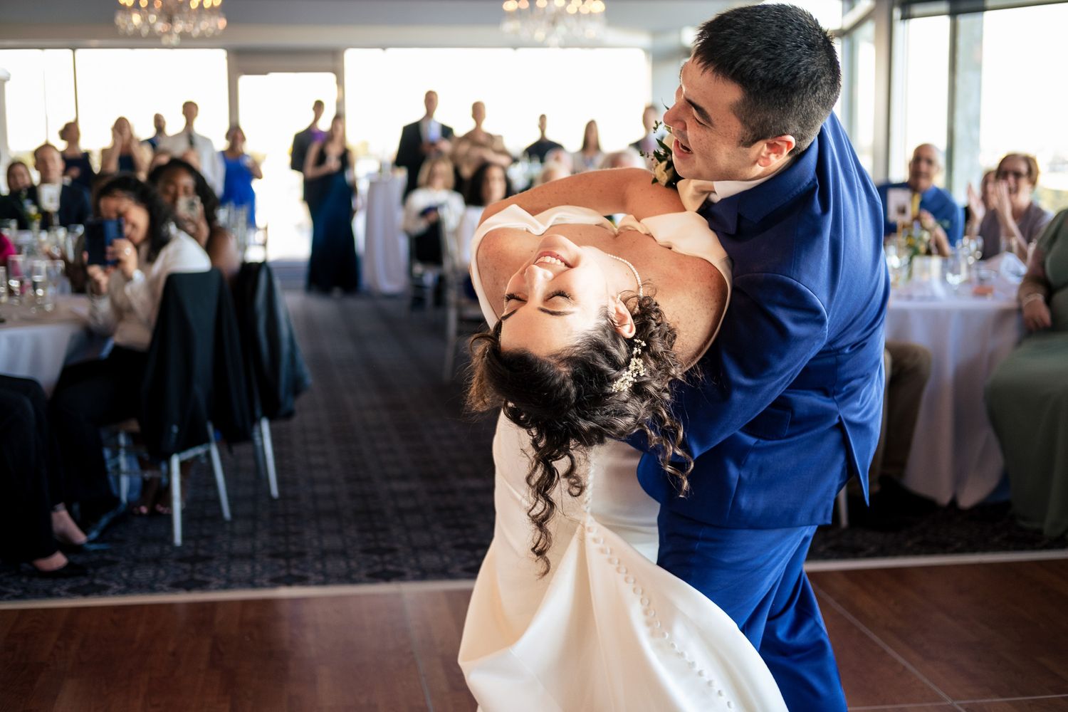 Groom dips bride dramatically during first dance at elegant wedding reception.