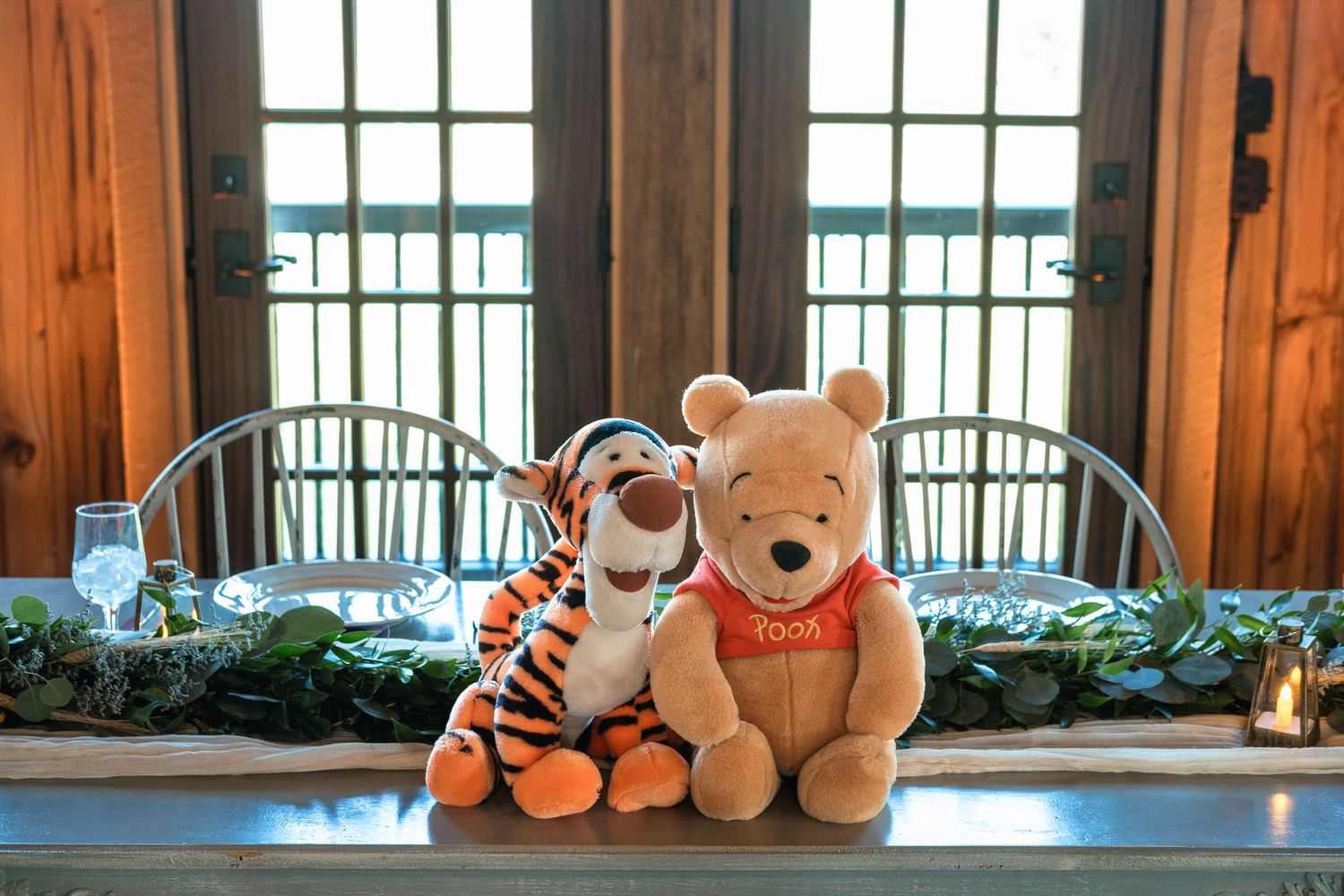 Winnie the Pooh and Tigger stuffed animals displayed as wedding decor on table in rustic barn.