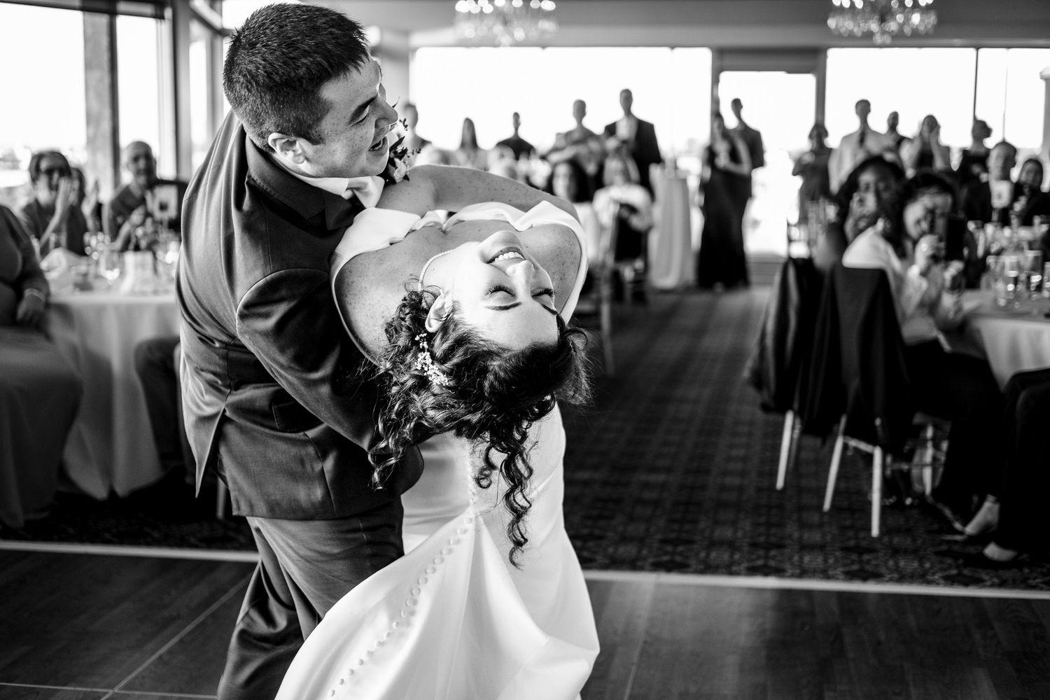 Groom dipping bride dramatically during romantic first dance at wedding reception.