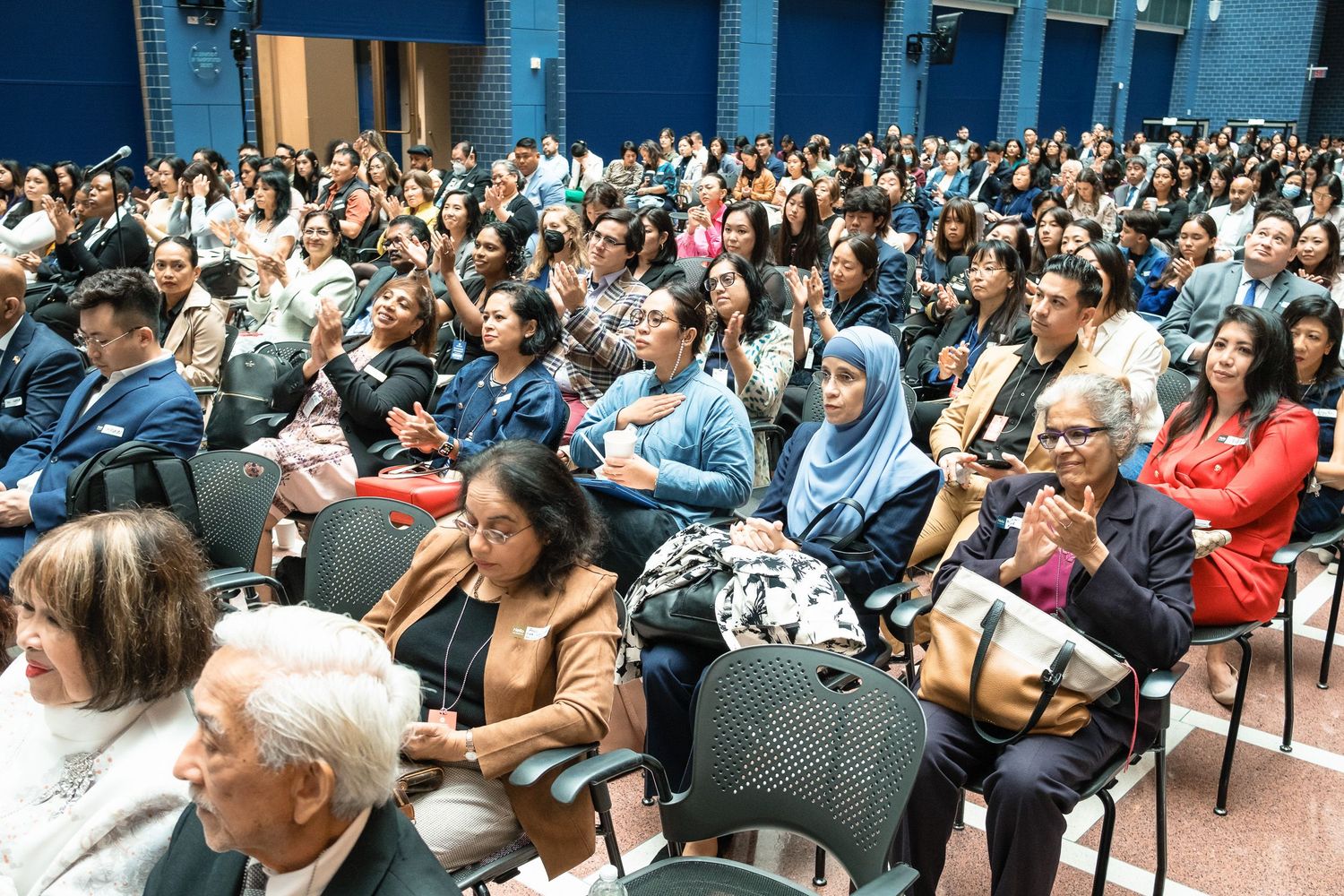 Diverse audience of people seated in an auditorium, attentively listening during a large community event or conference.