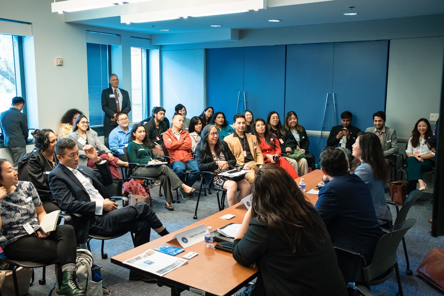 Diverse group of professionals attending a seminar in a modern conference room with blue walls.