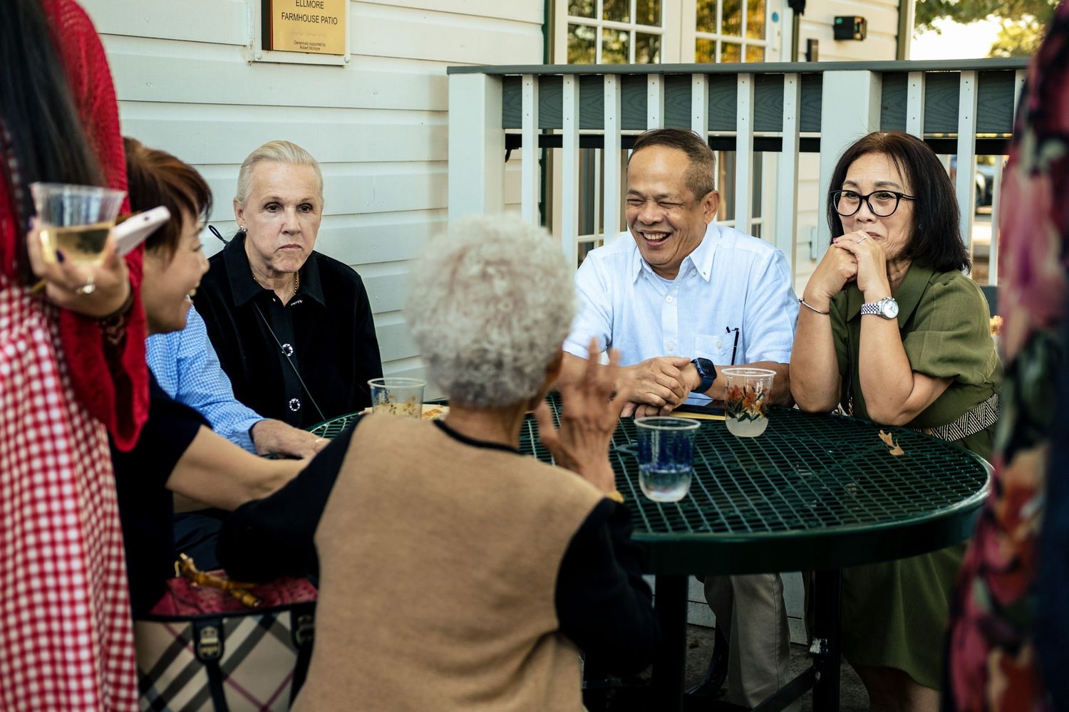 Wedding guests socializing at an outdoor patio table during an evening reception gathering.