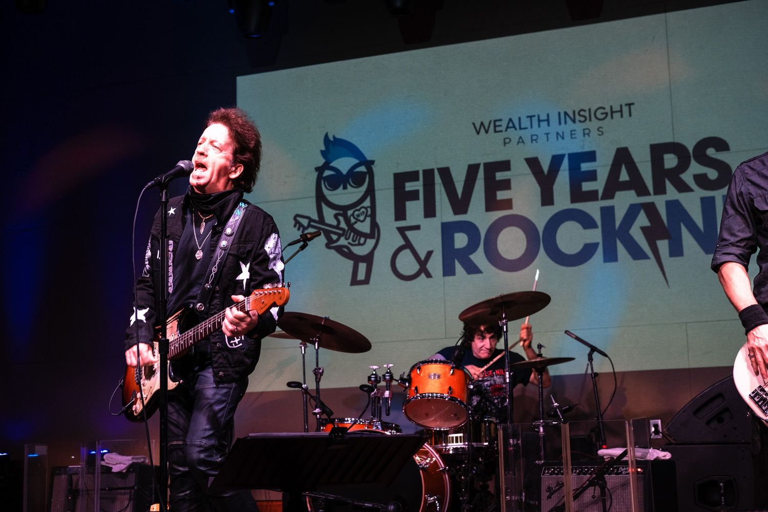 Live band performing on stage at Wealth Insight Partners Five Years & Rock-N Roll anniversary celebration.