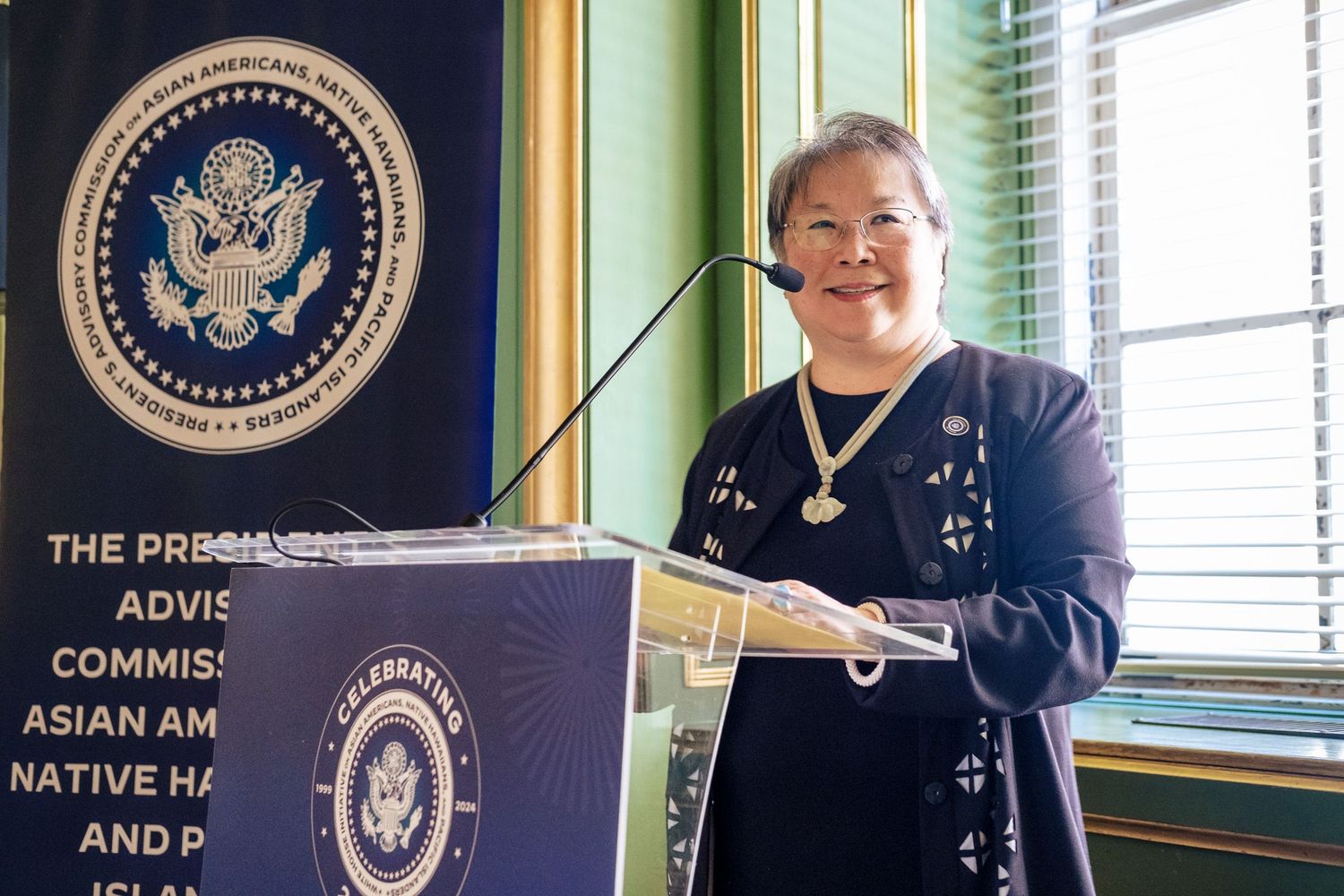 Woman speaking at podium before Presidential Advisory Commission on Asian Americans, Native Hawaiians, and Pacific Islanders.
