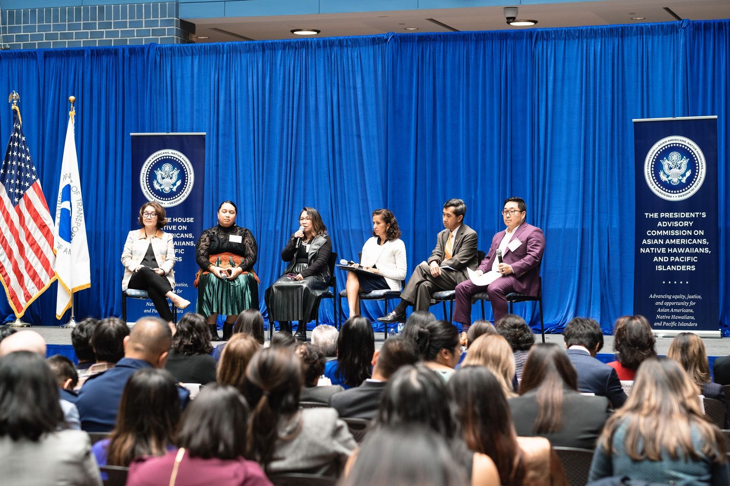 Panel discussion at President's Advisory Commission on Asian Americans event with six speakers on stage before a large audience.
