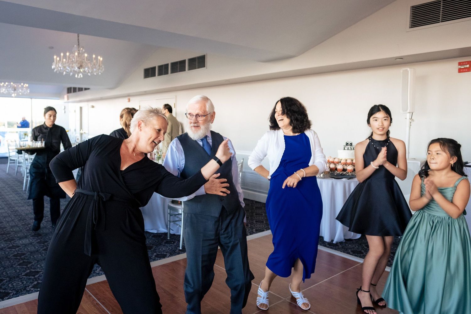 Guests dancing joyfully together at wedding reception in elegant ballroom venue.