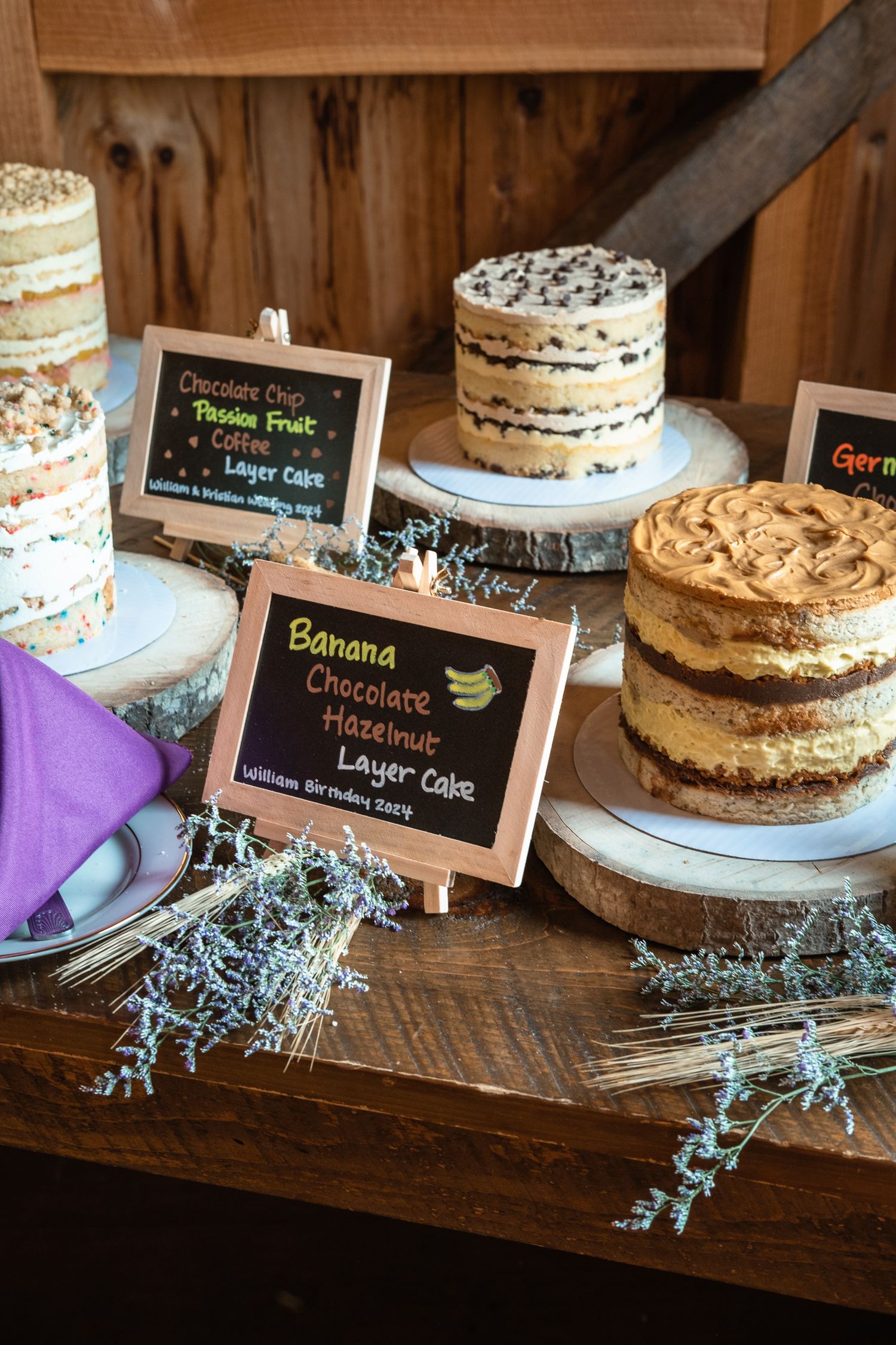 Wedding dessert table with banana chocolate hazelnut and German layer cakes on wood stands.