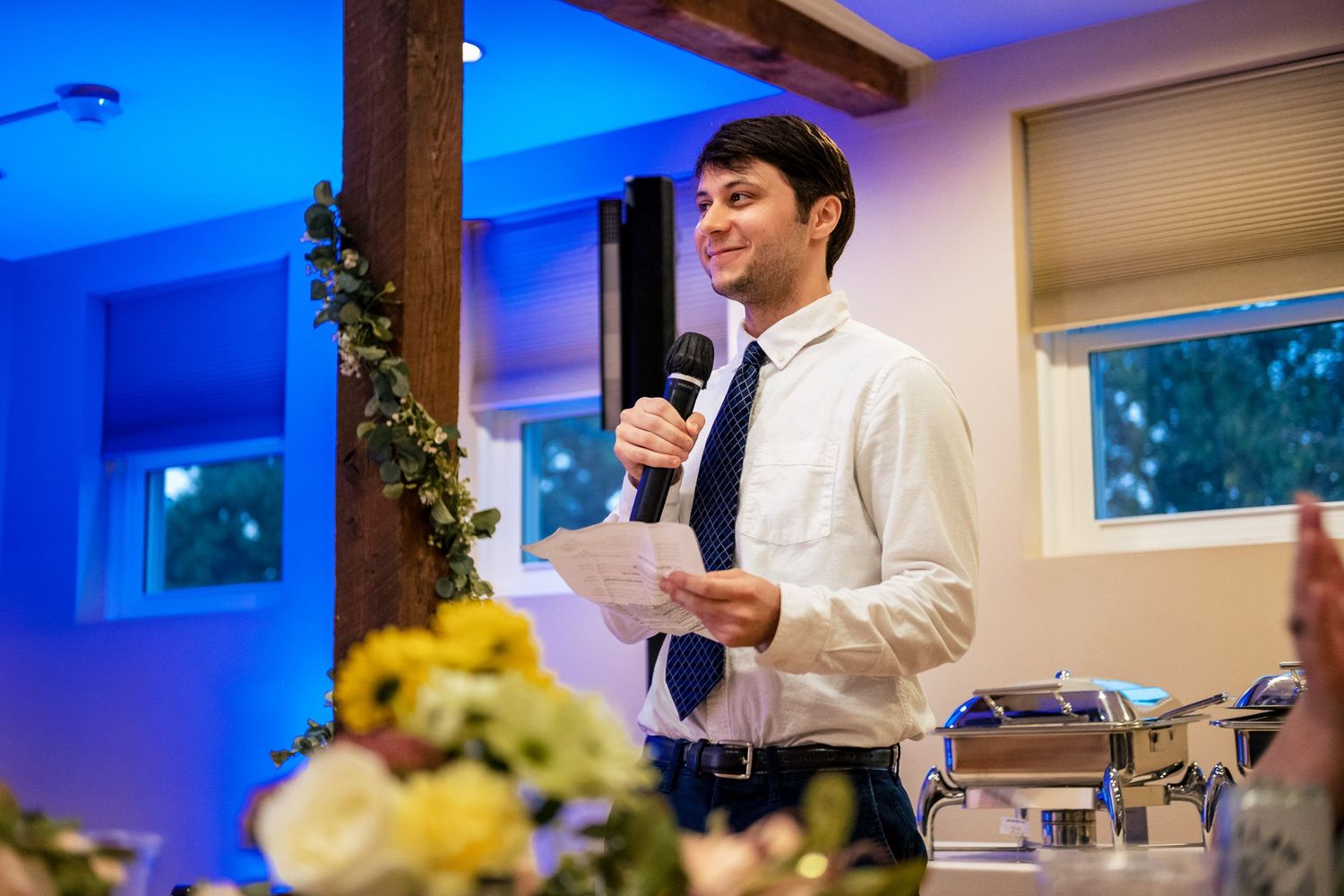 Young man in white shirt and tie delivering a wedding speech at the reception.