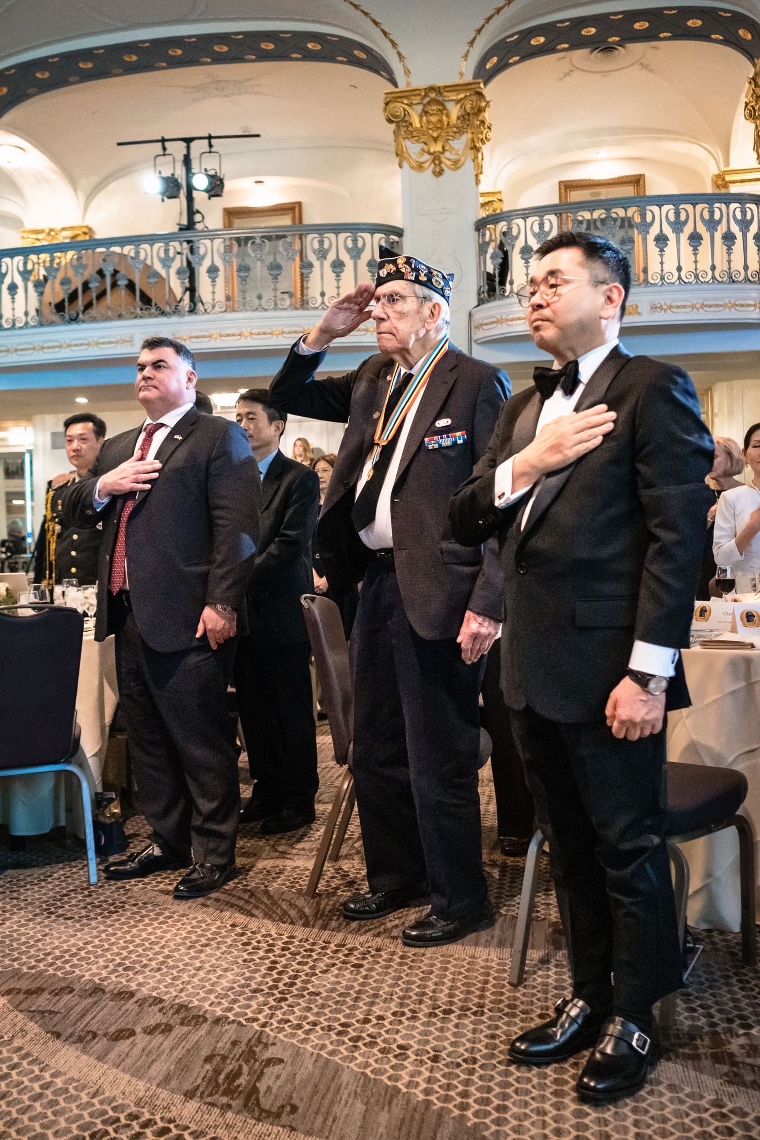 Three men in formal attire stand at attention during a ceremony at the Korean War Veterans Memorial Foundation gala.