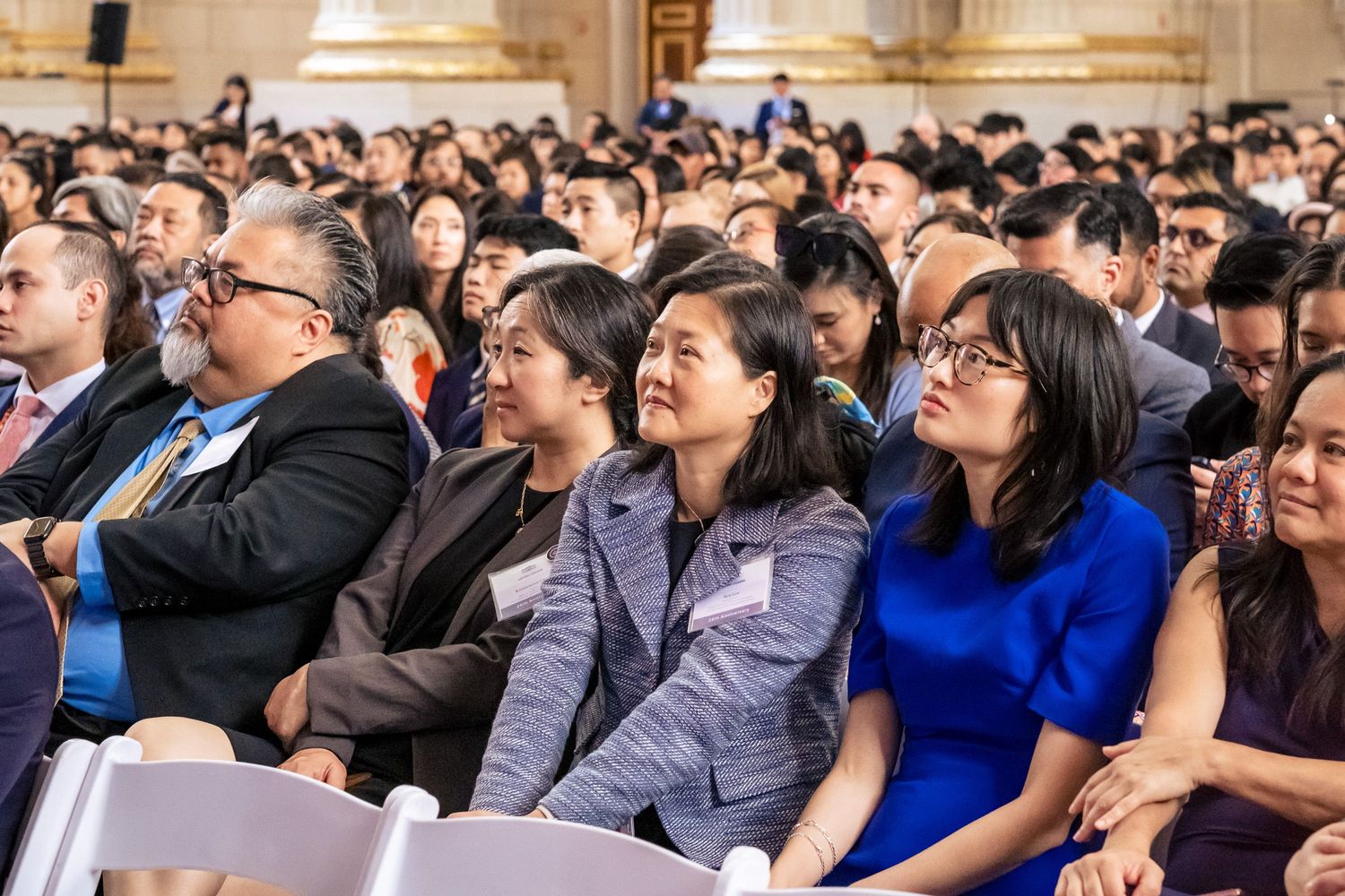 Diverse audience of Asian professionals seated at a formal event or conference in an elegant hall.