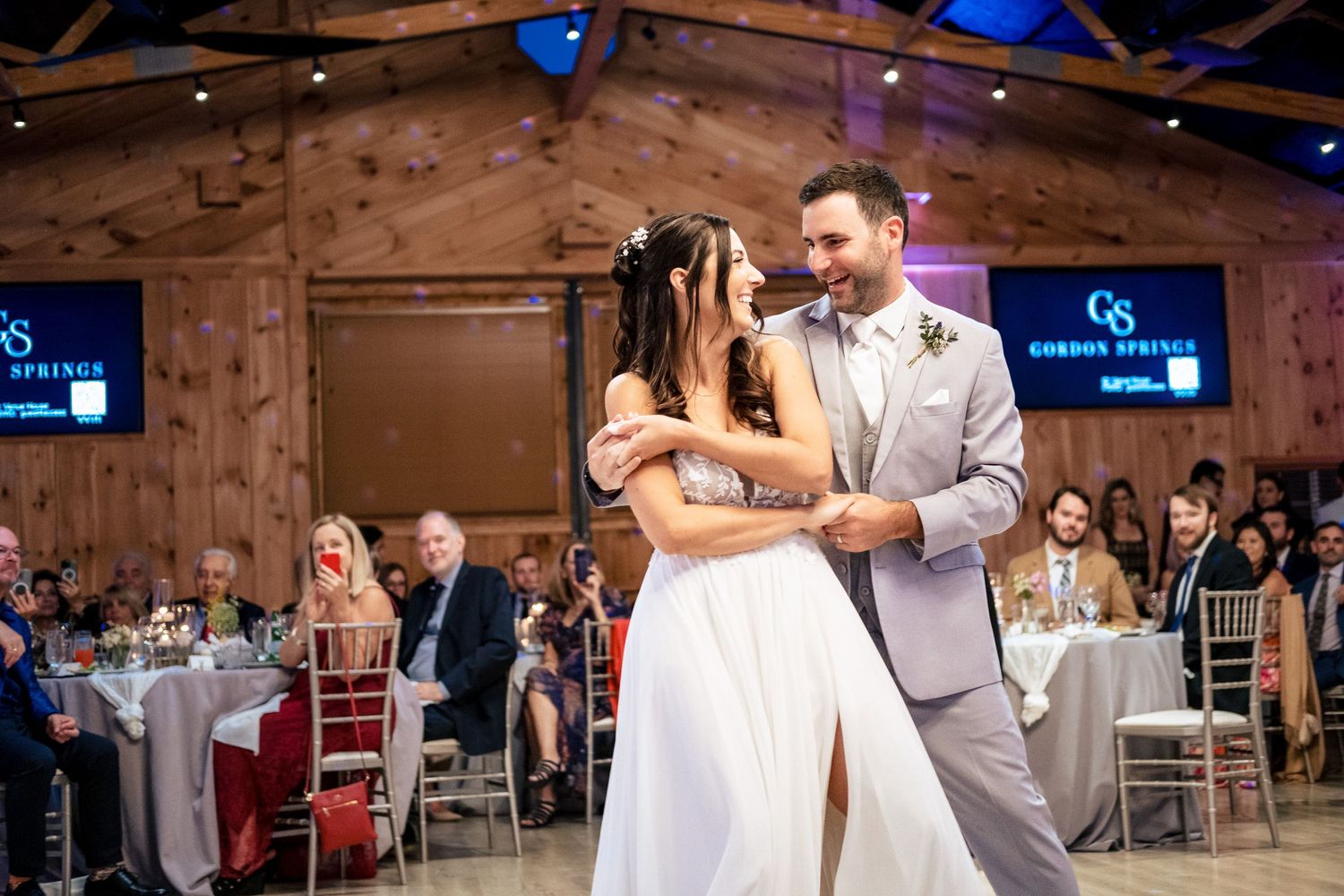 Bride and groom sharing romantic first dance in rustic barn wedding venue.