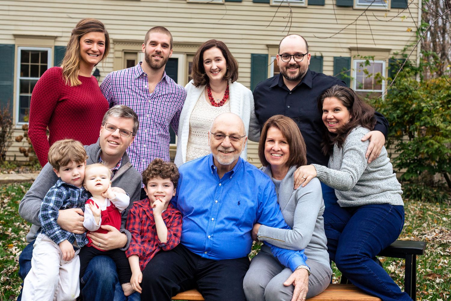 Large multigenerational family posing together outdoors in autumn for a group portrait photo.