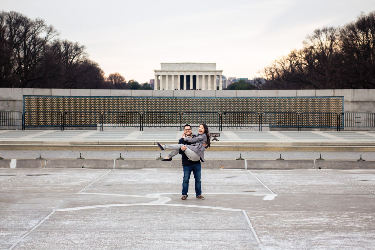 Couple embracing in front of the Lincoln Memorial in Washington DC during an engagement photo session.