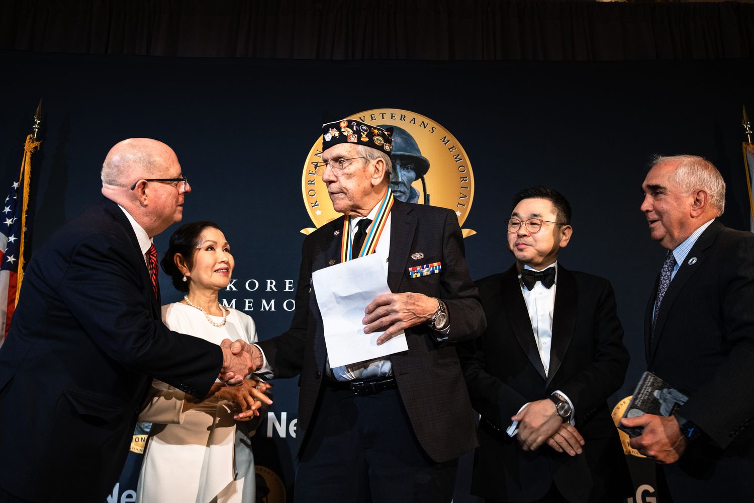 Veterans and dignitaries shake hands at Korean War Veterans Memorial Foundation ceremony.